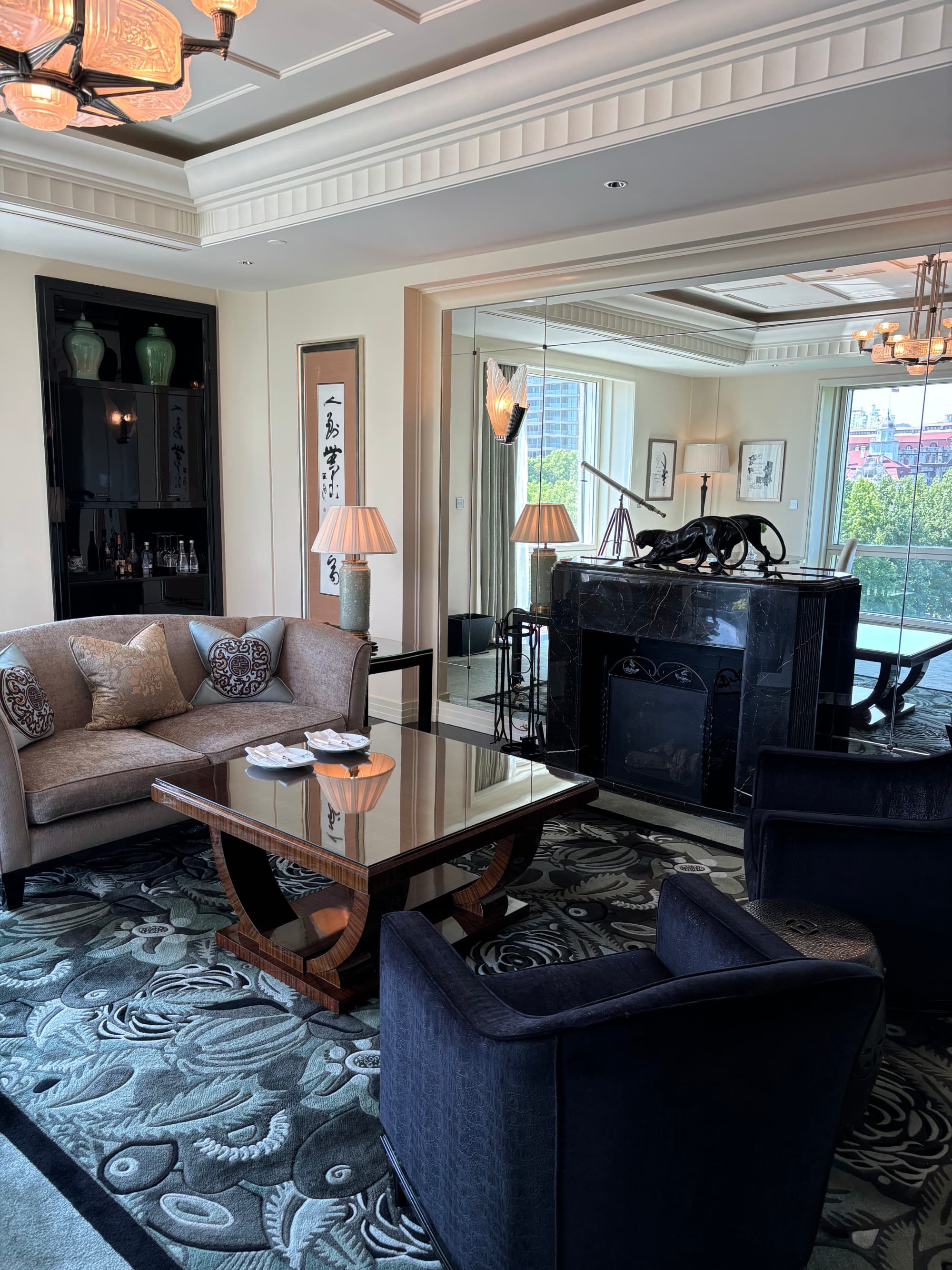 A seating area with a beige couch and two black chairs in a hotel room