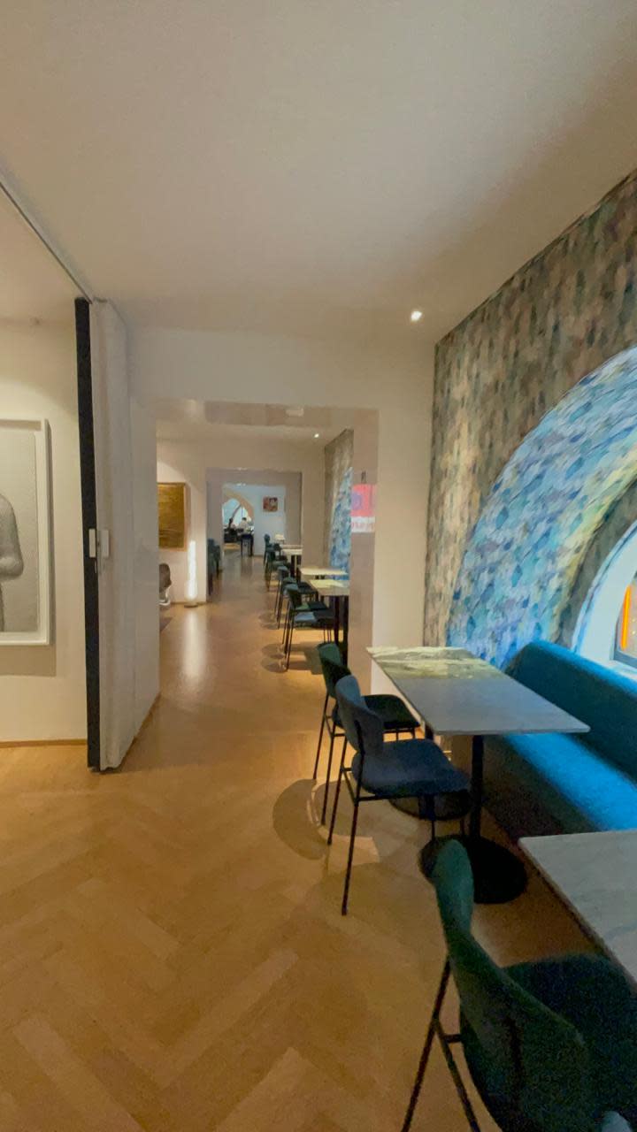 A hallway in a hotel with a seating area of blue chairs