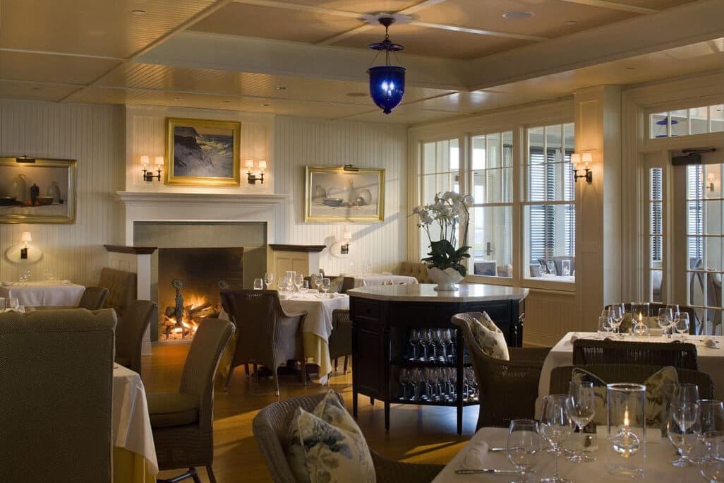 a dimly lit restaurant dining room with a large fireplace