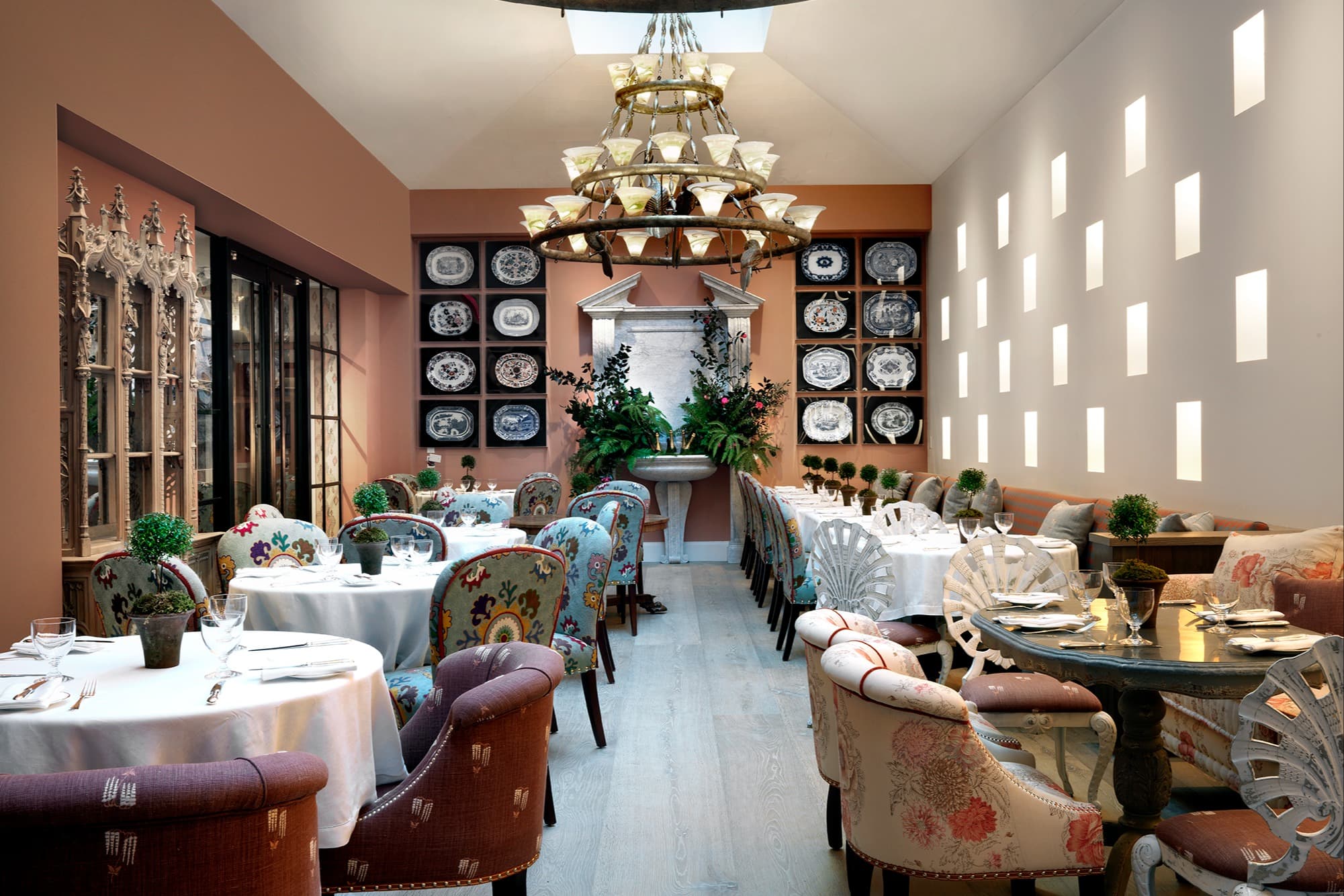 a fancy dining room with a tiered chandelier and circular tables covered with white tablecloths