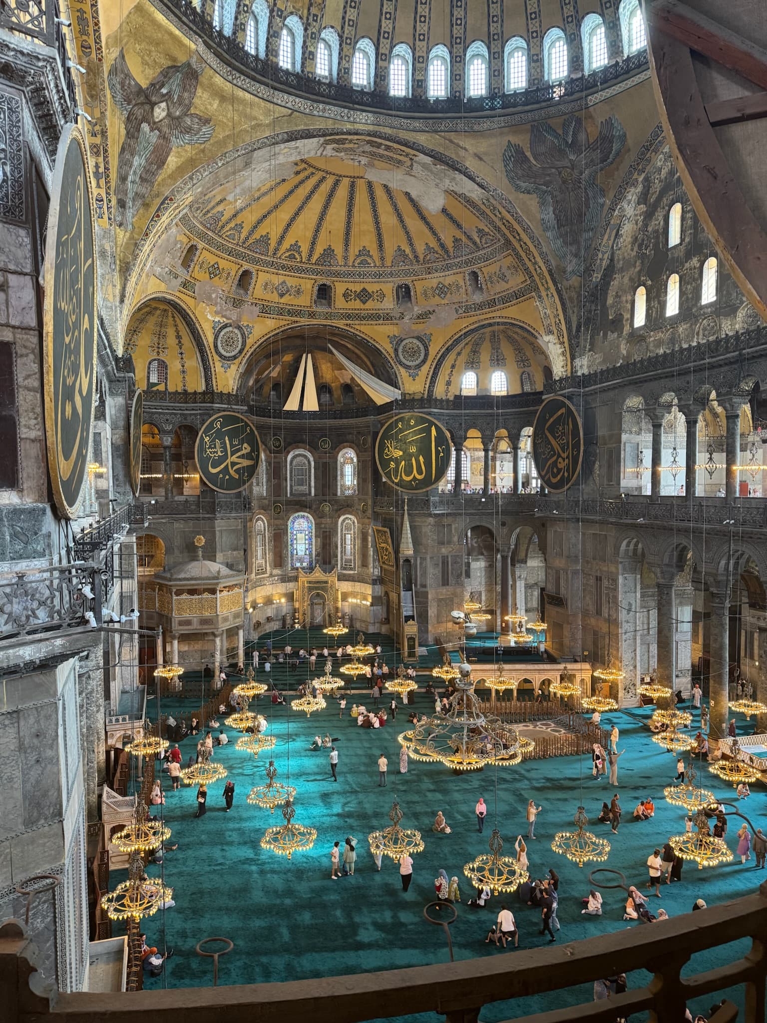 The inside of a decorated, ancient building with bright blue carpet and domed ceilings