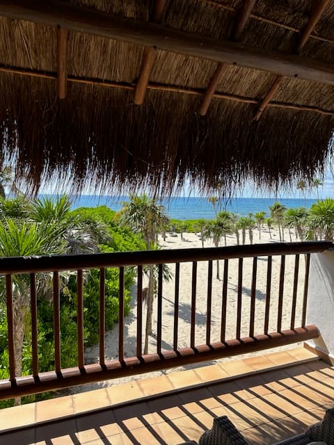 View from the balcony of a bungalow looking at the beach during the day.