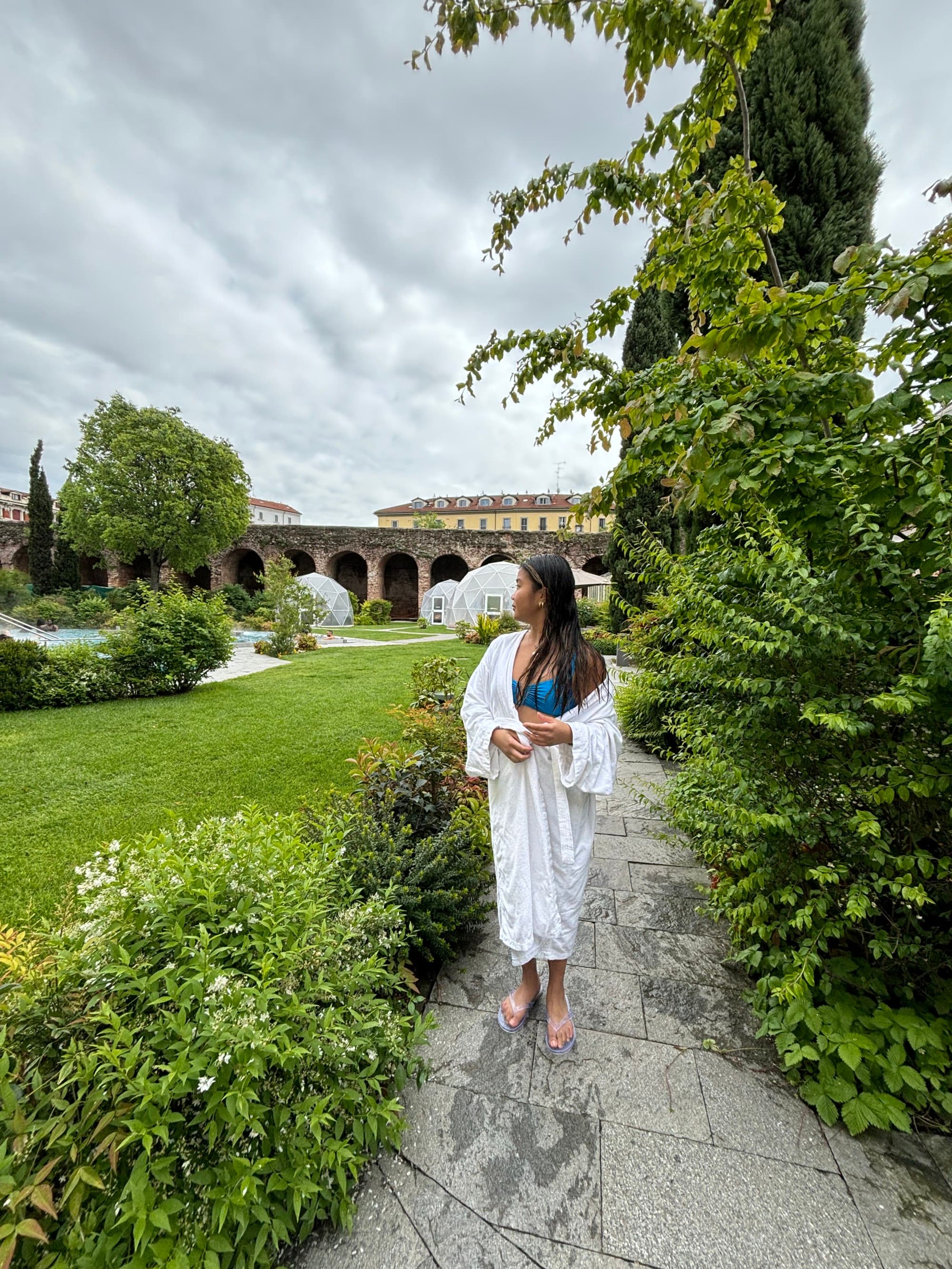 A person standing in a pathway outside while wearing a white spa robe