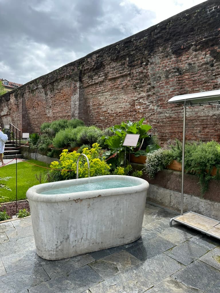 An outside bathtub in front of a brick wall