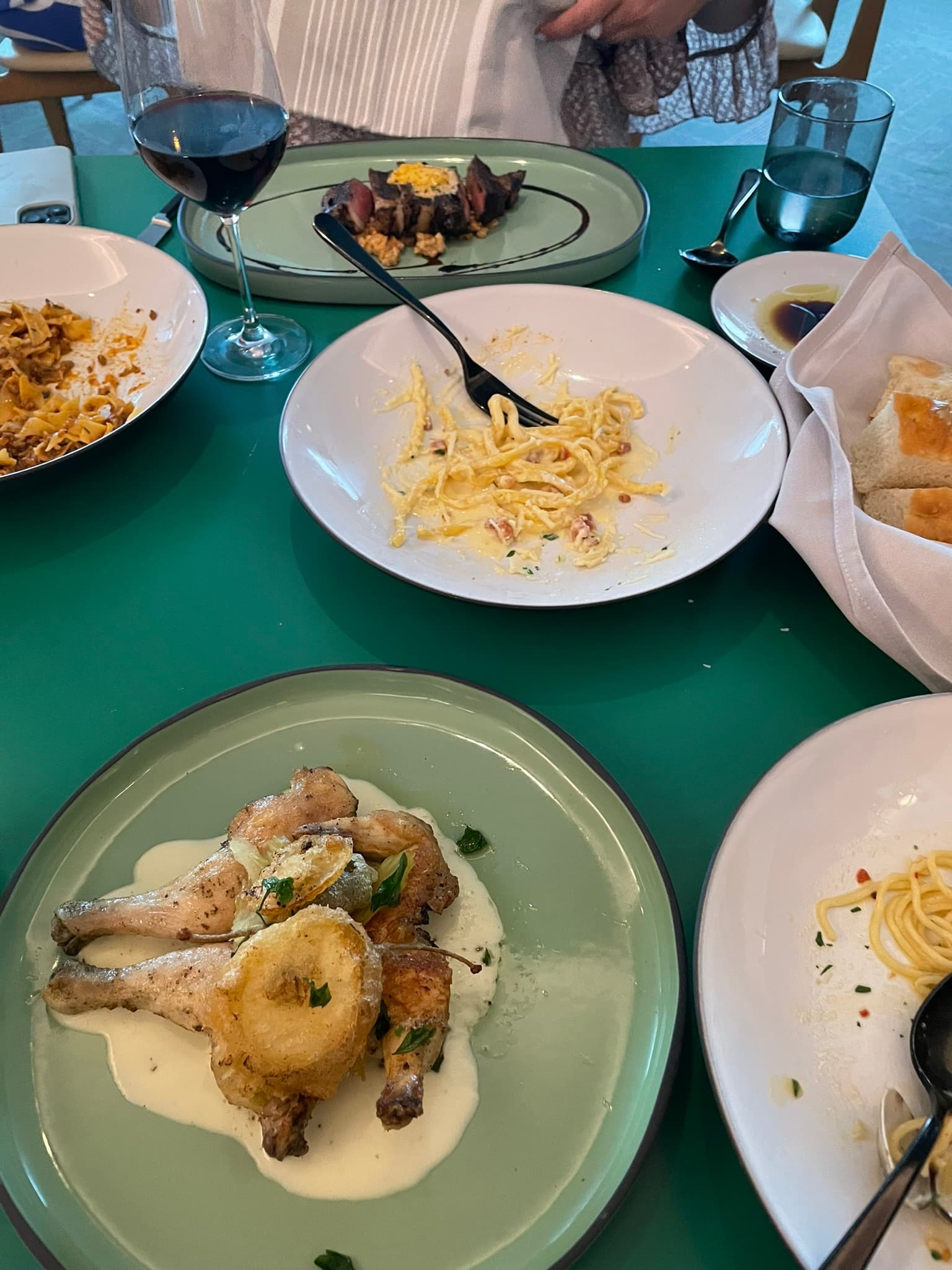 A selection of food dishes including pasta and seafood all arranged on a green table.