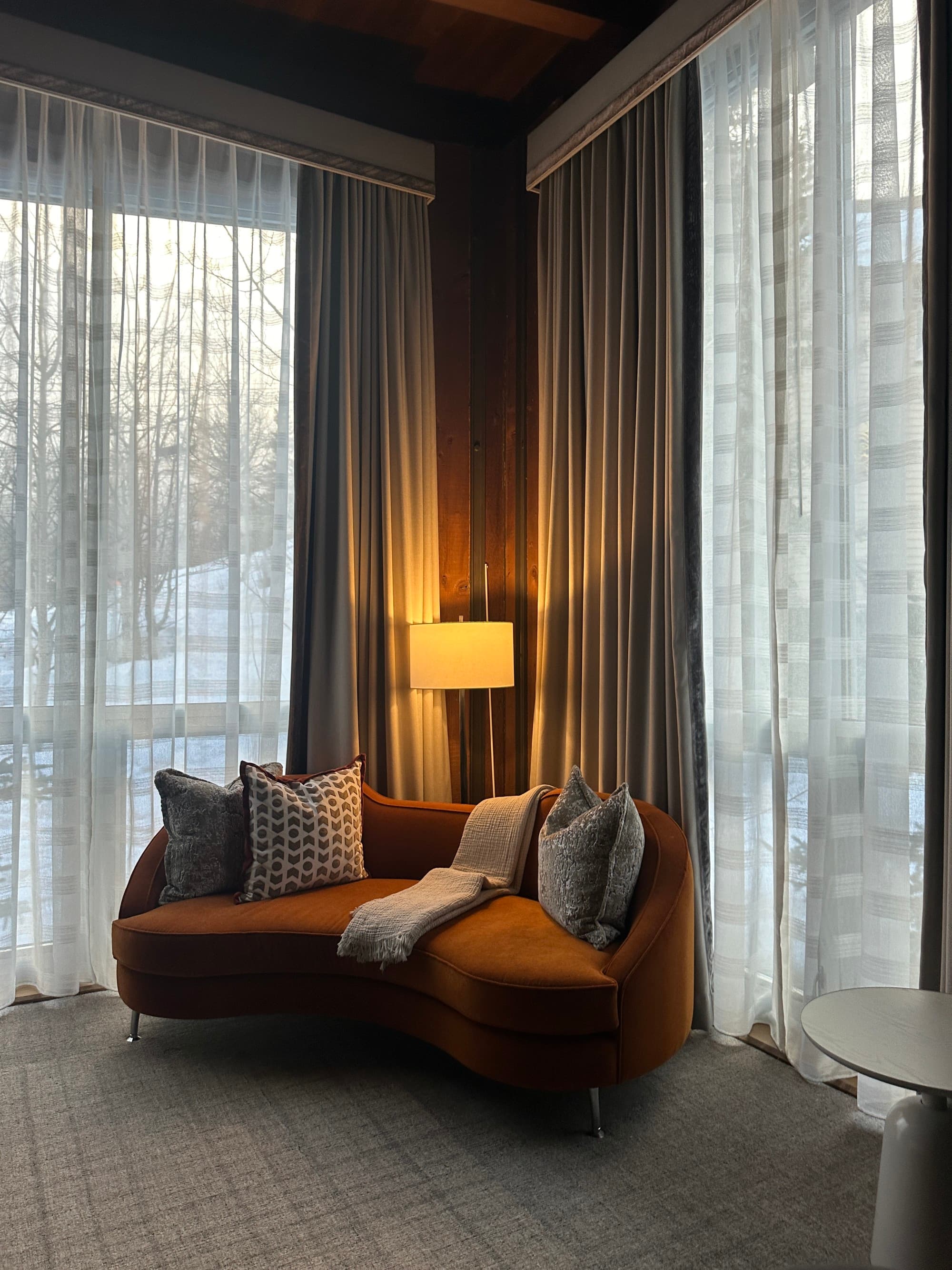 A cozy corner of a room with a lamp and dark orange corner sofa in Aspen in the fall.