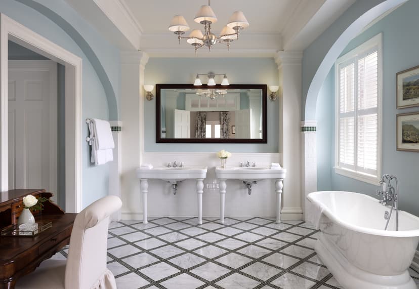 blue-walled bathroom with a white tub and his and hers white sinks