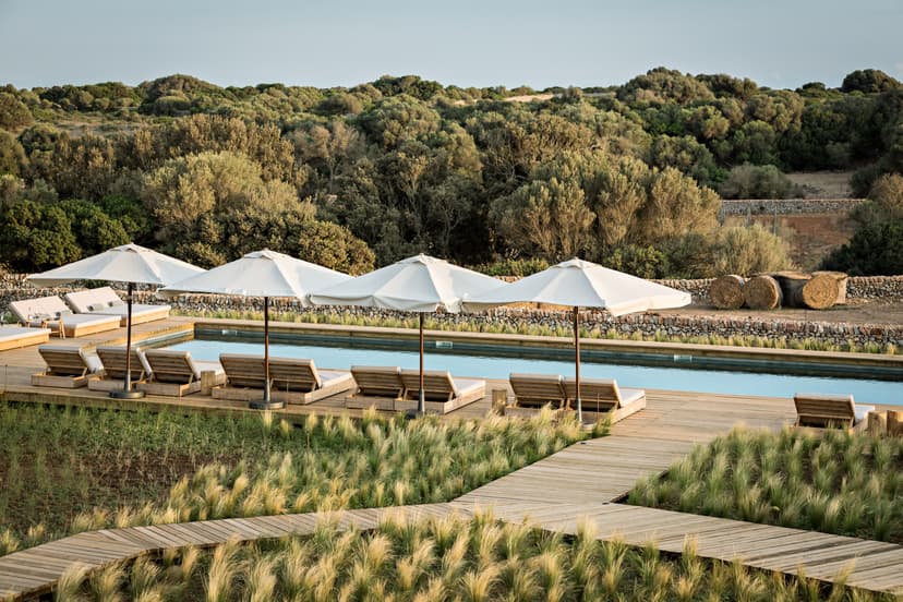 umbrellas and white loungers on a wooden deck near a pool