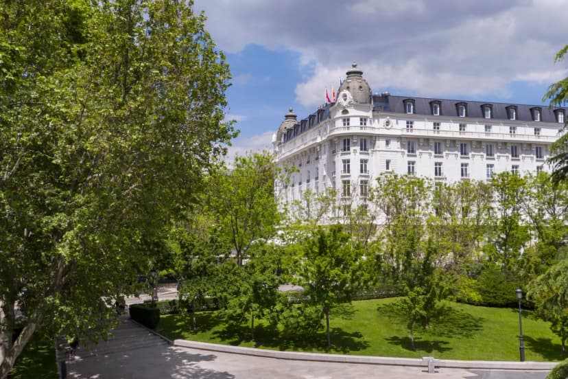 a regal white multi-story building surrounded by trees and a grassy lawn