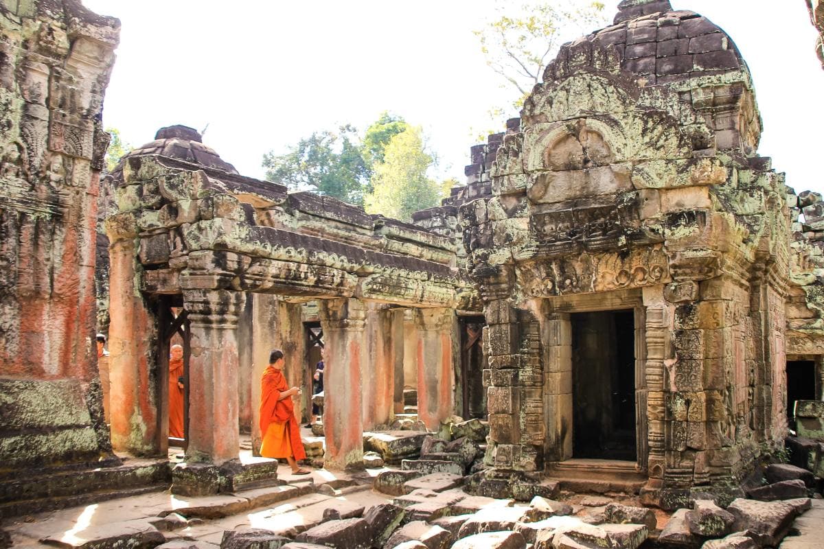 Two monks in orange walking through ancient ruins in Siem Reap.