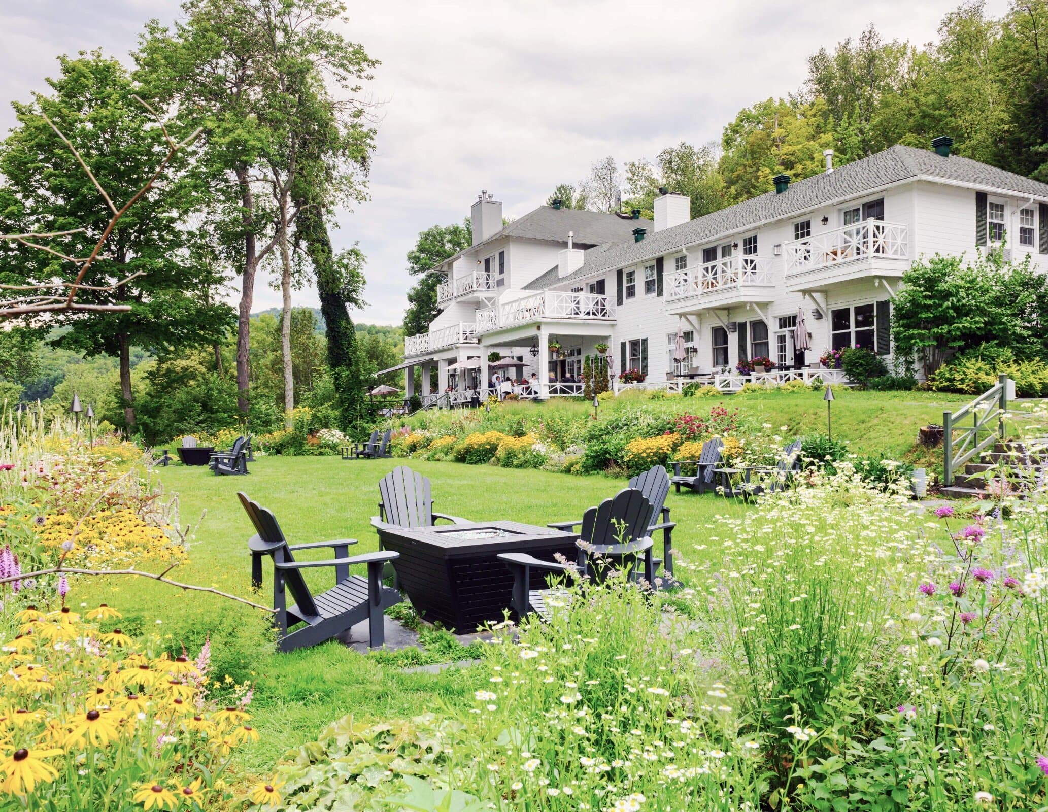 The hotel and its sprawling grounds with lush foliage and a patio table and chairs set in the garden.