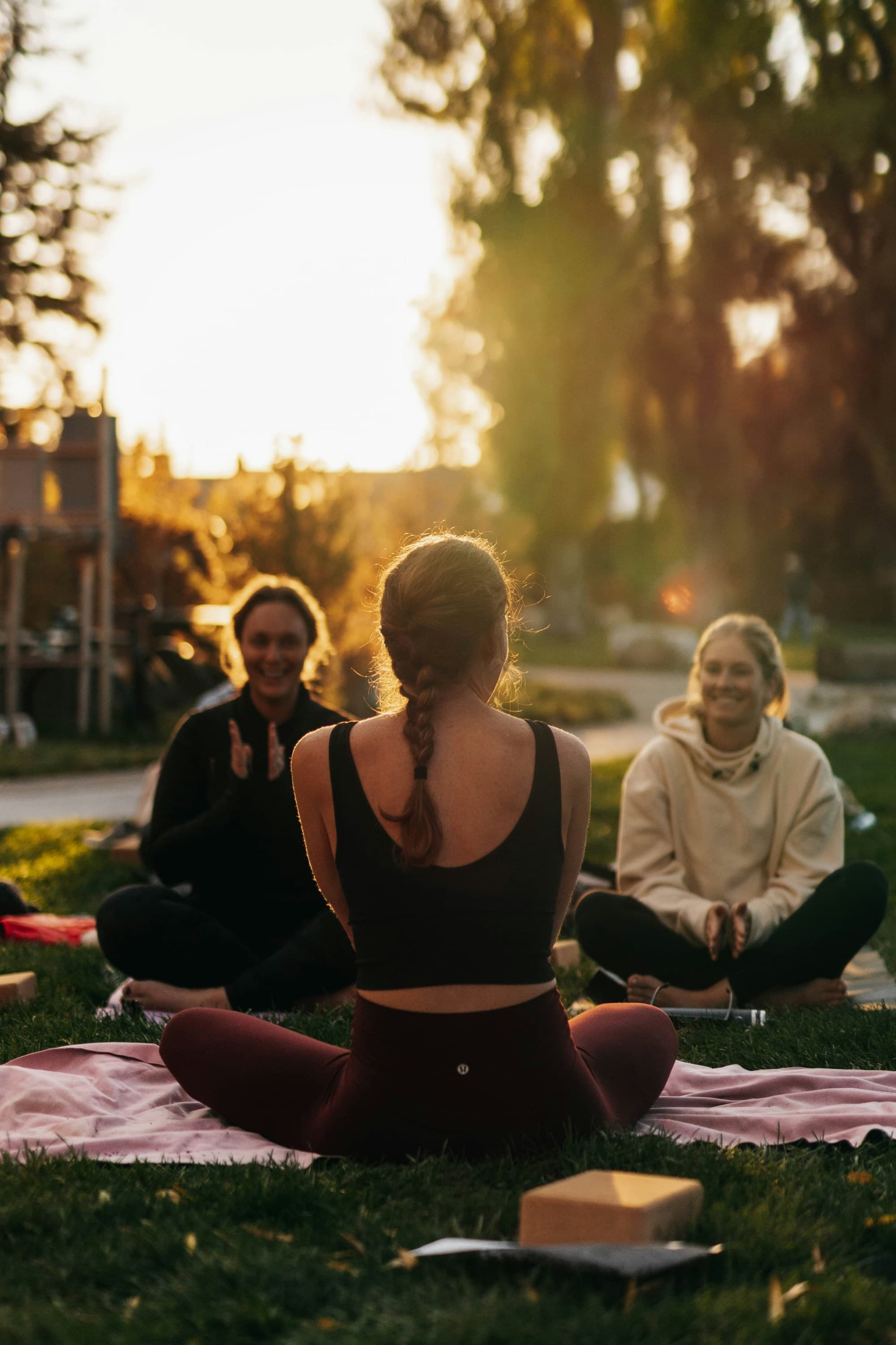 Group of women sitting outside on yoga mats