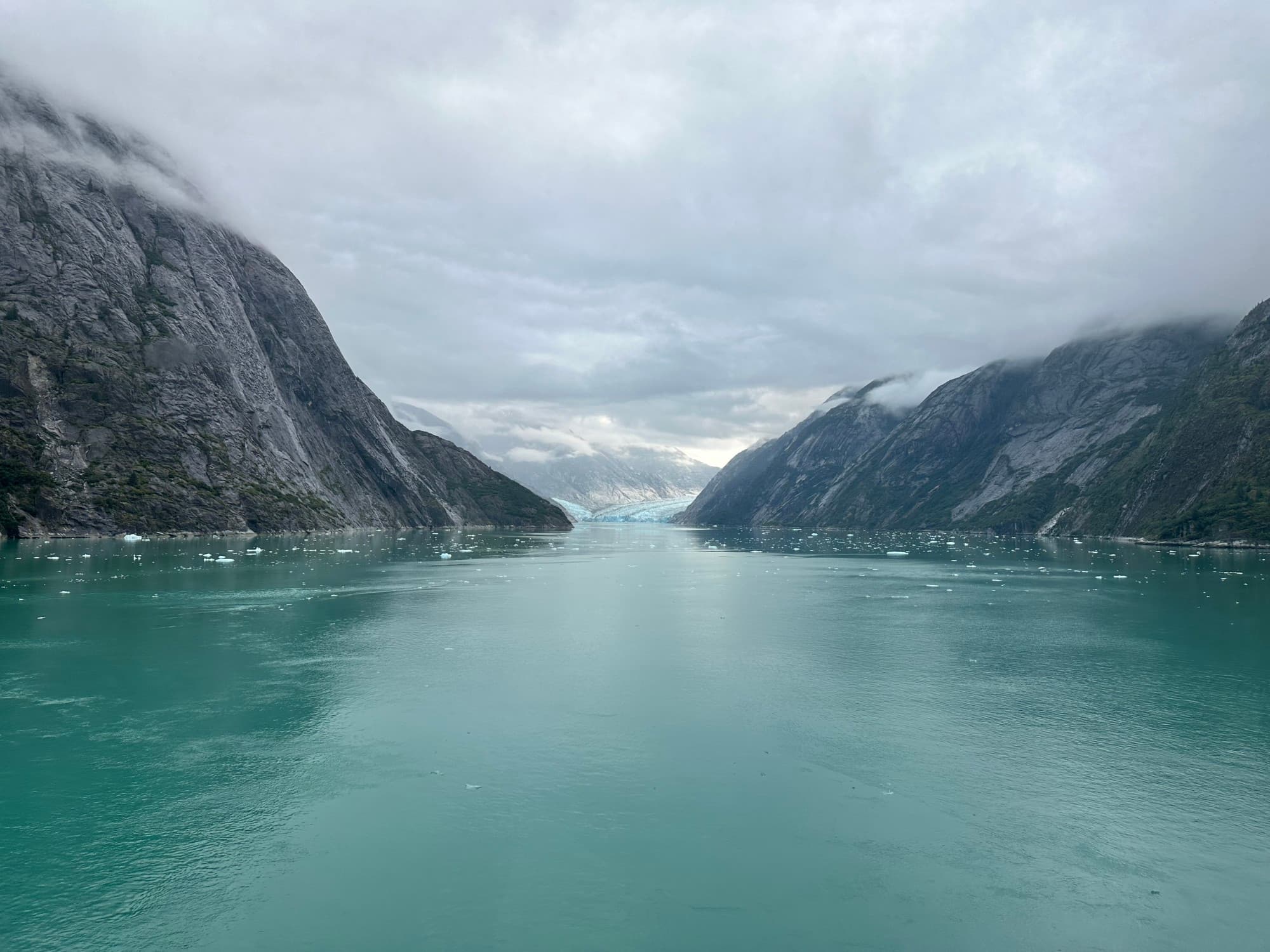 A body of water between two rocky hills during a foggy day