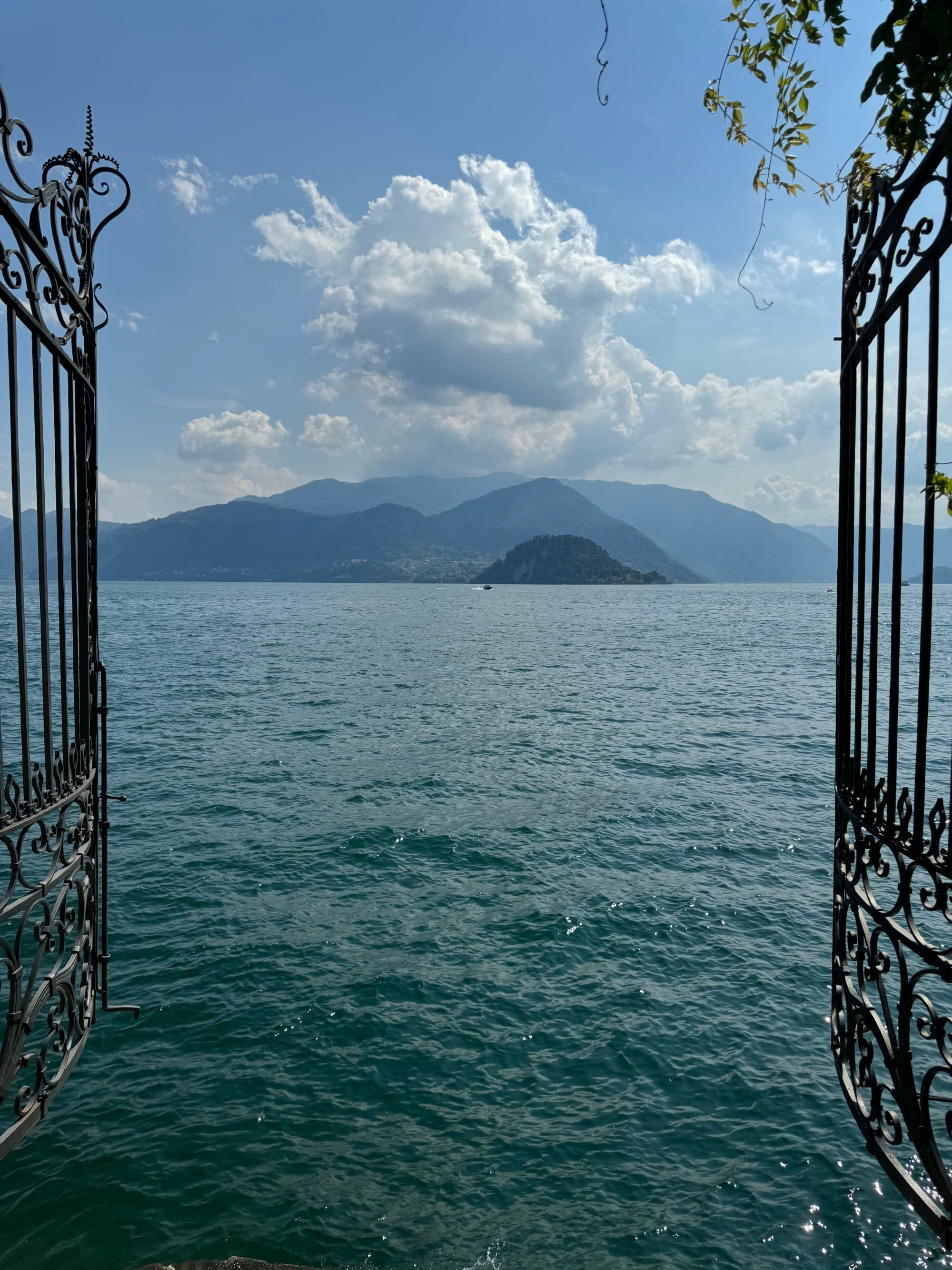 Two black gates open to reveal a lake with mountains in the distance