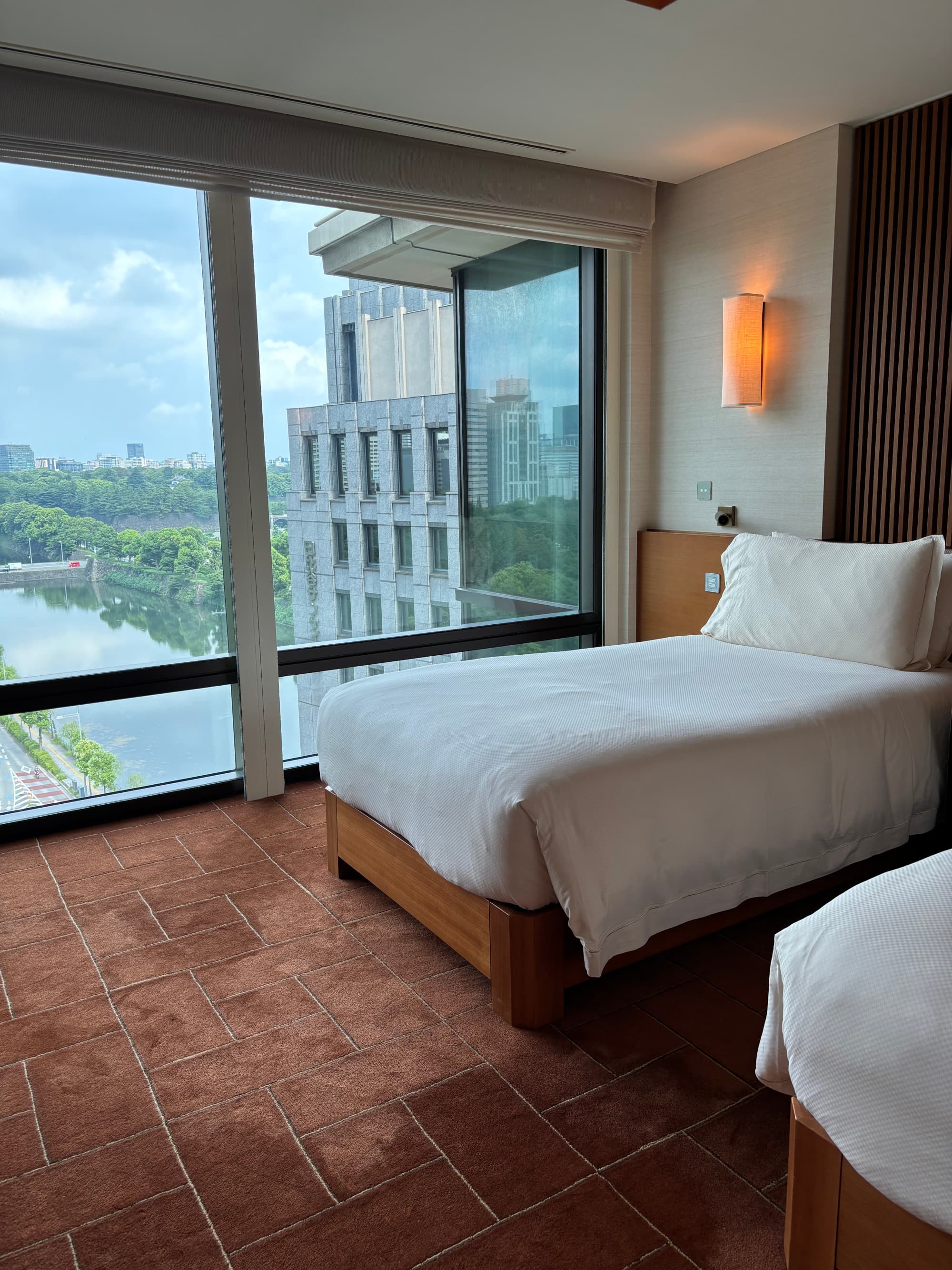 A hotel room with two white beds and a large, floor-to-ceiling windows