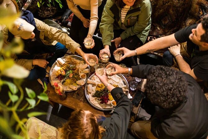 A view from above of a group of people sharing a meal and holding their glasses out to toast.during a food tour in Cape Town.