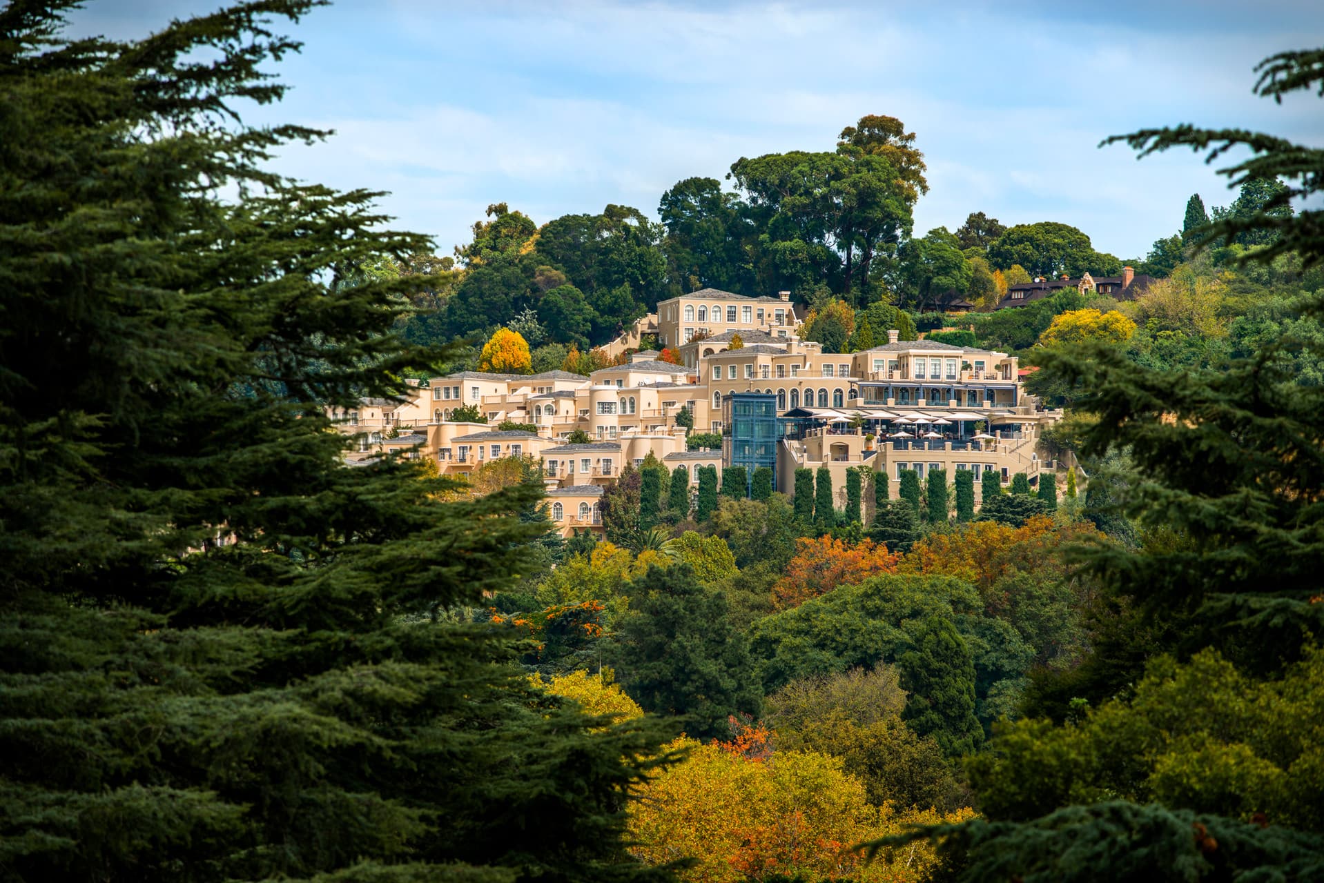 The exterior of the Four Seasons South Africa surrounded by lush forest landscape with yellow, green and orange foliage.