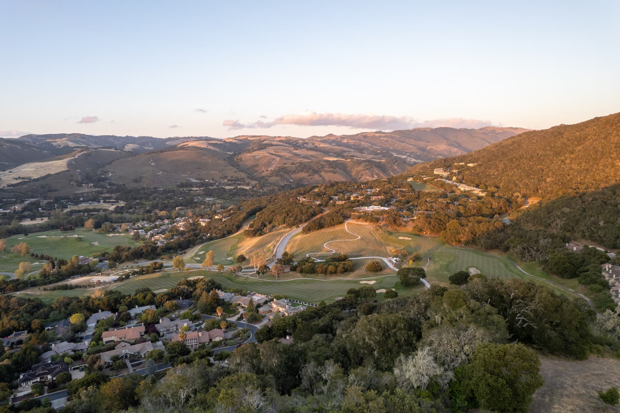 A view of Carmel Valley from above, with rolling hills, a small collection of houses and clouds in the distance - shot by The Nomadic People