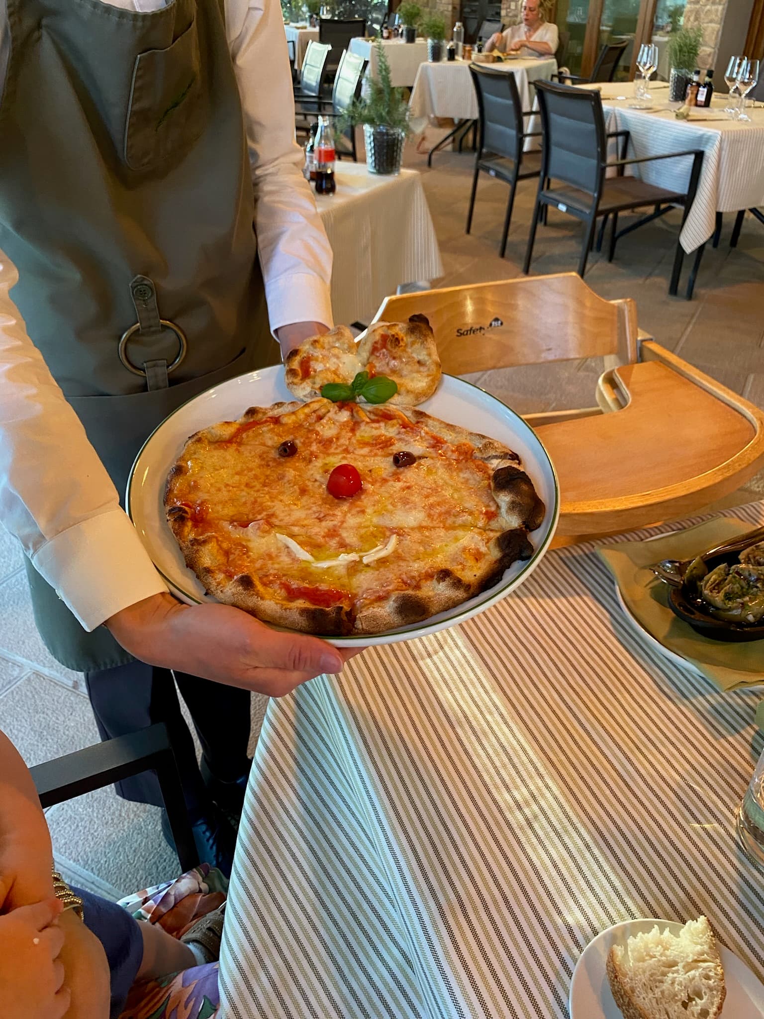 A person holding a pizza decorated with a face at Castelfalfi, Tuscany.