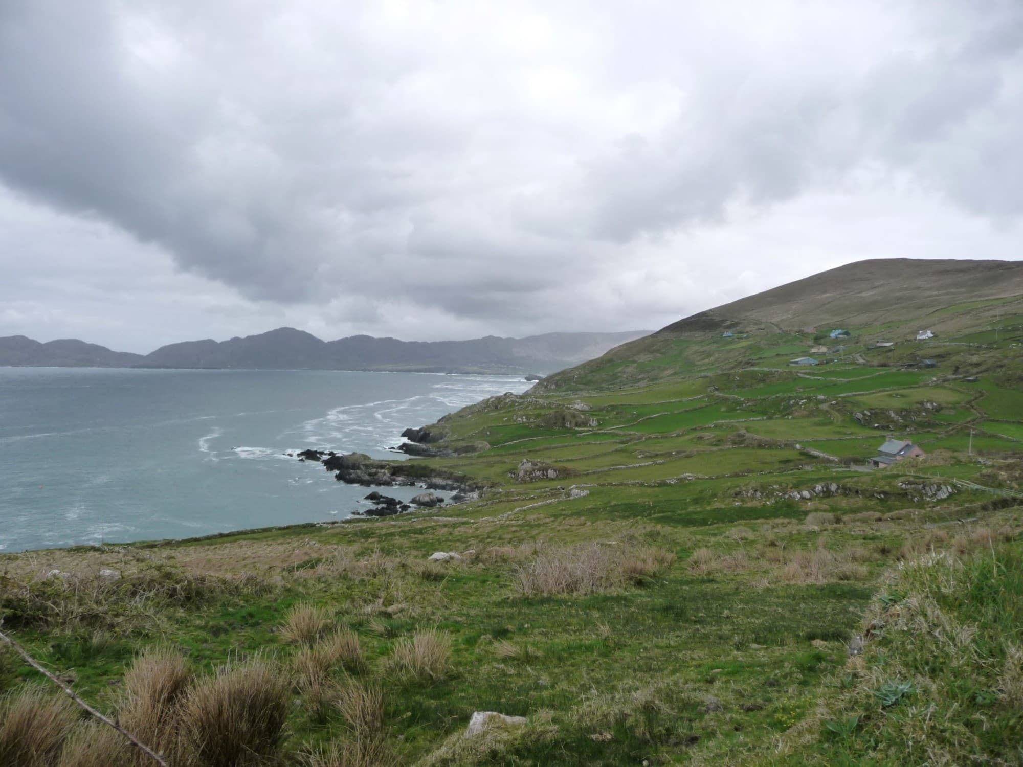 Sea next to grassy hills during a cloudy day in Ireland in May.