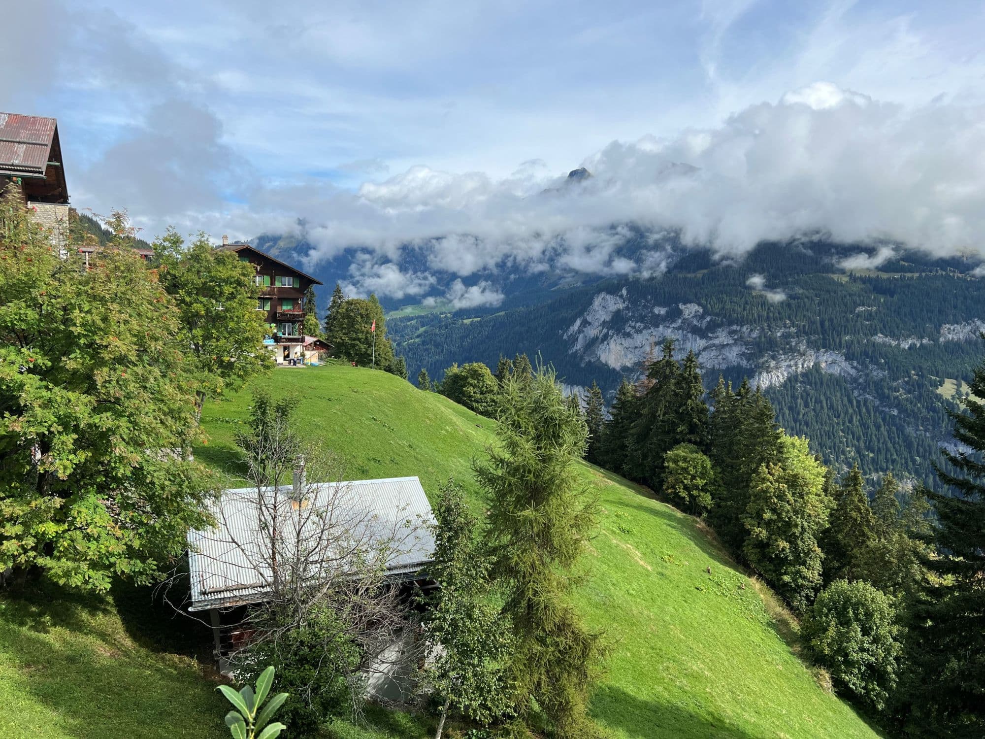 A view of Switzerland's mountaintops, and wooden chalet-style houses, on a semi-cloudy day.