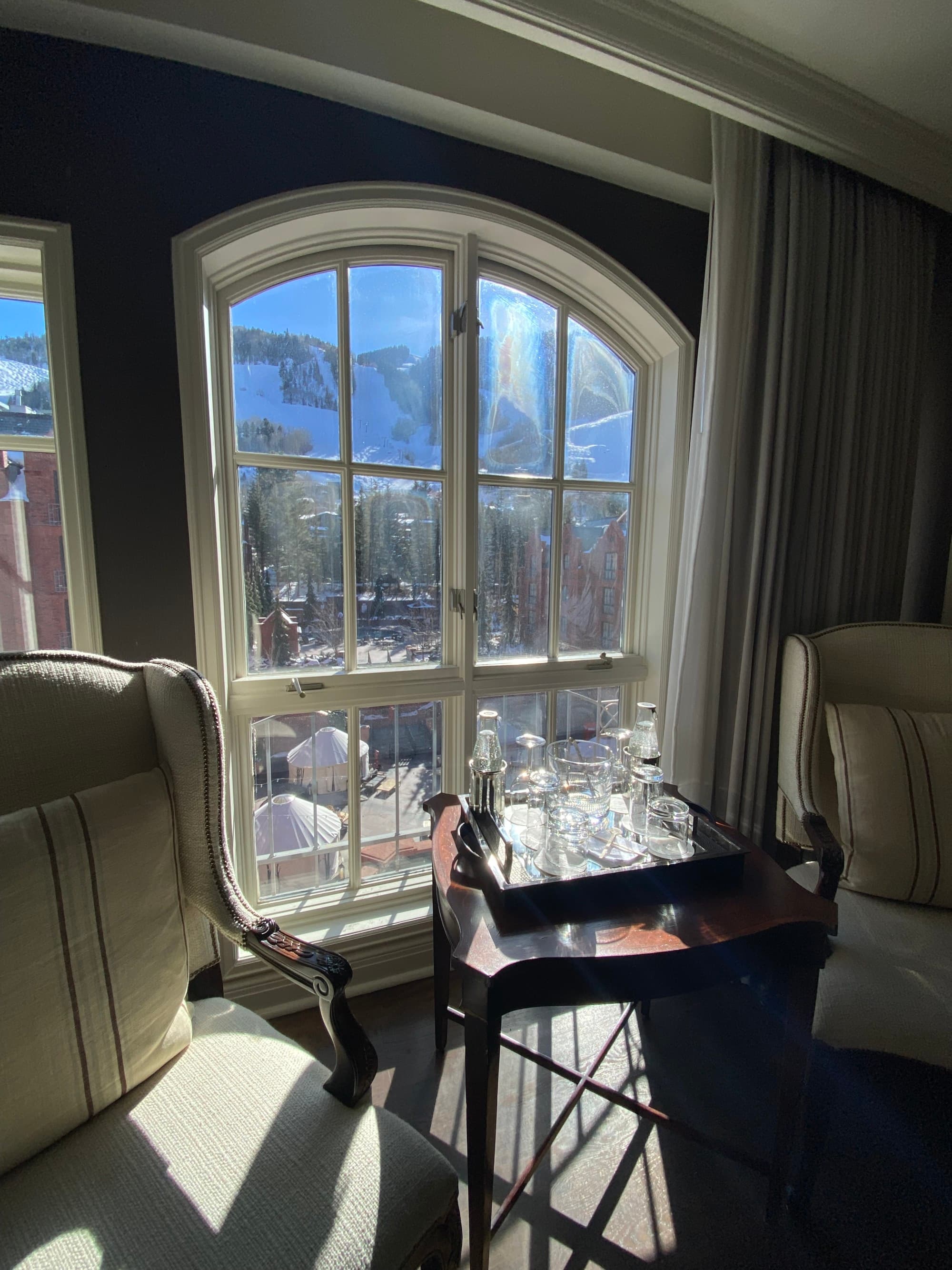 Inside a hotel room of the St. Regis, with a view through the grand windows of Aspen's mountains.