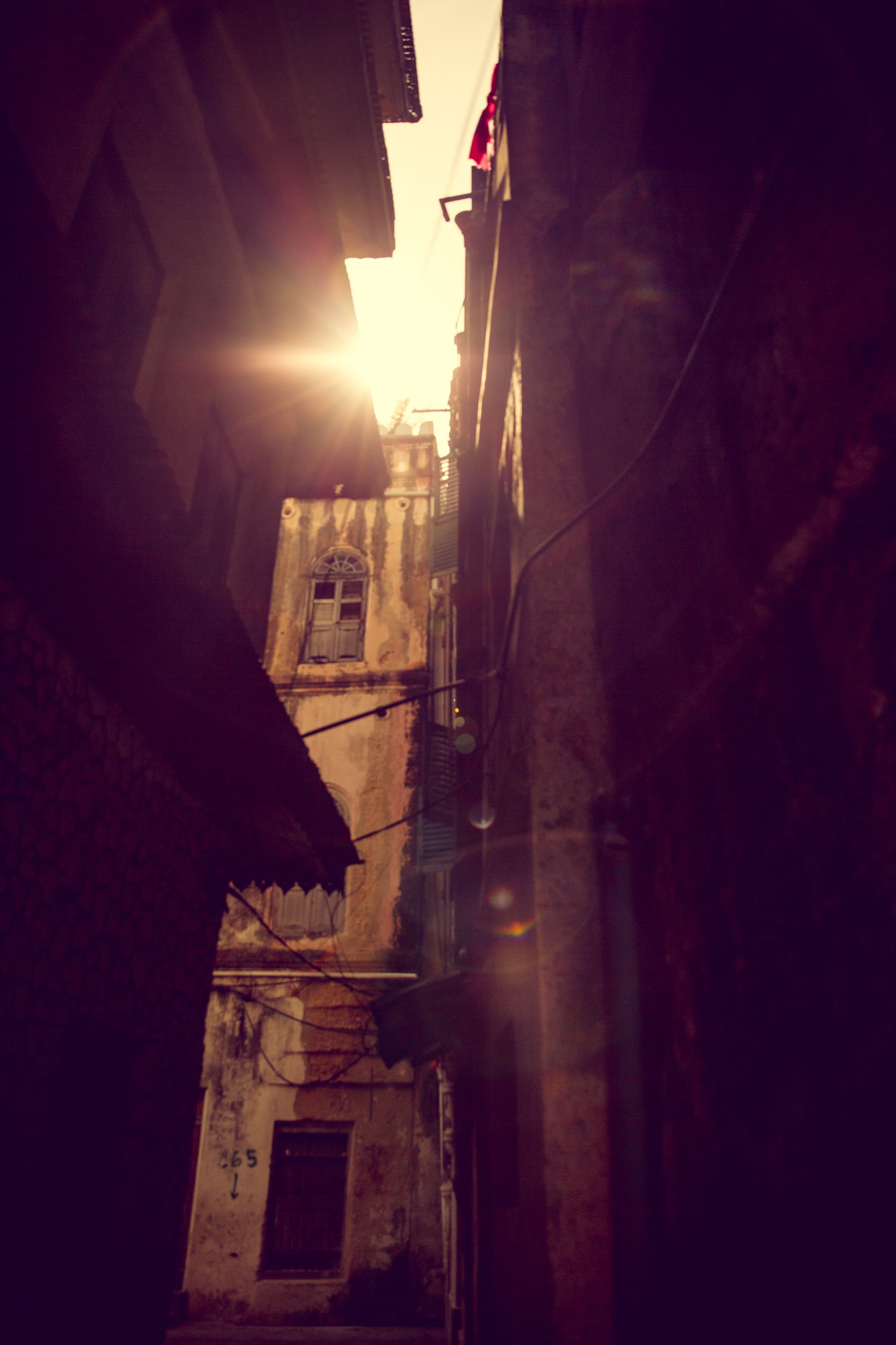 A view of stone buildings with a sliver of sunshine peeking through.