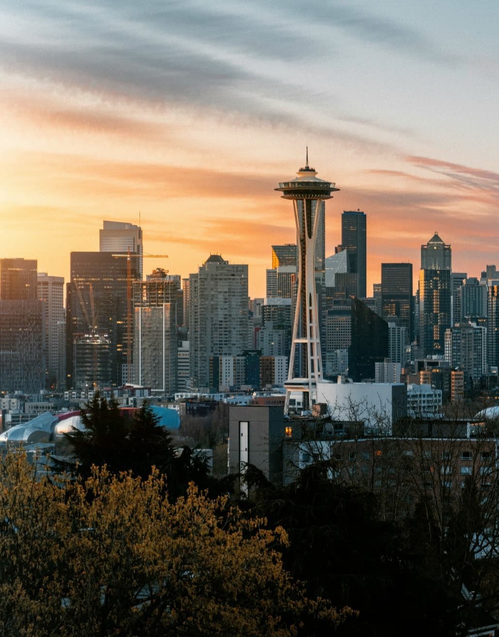 A view of the stunning Seattle skyline with a vibrant, orange sunset in the background.