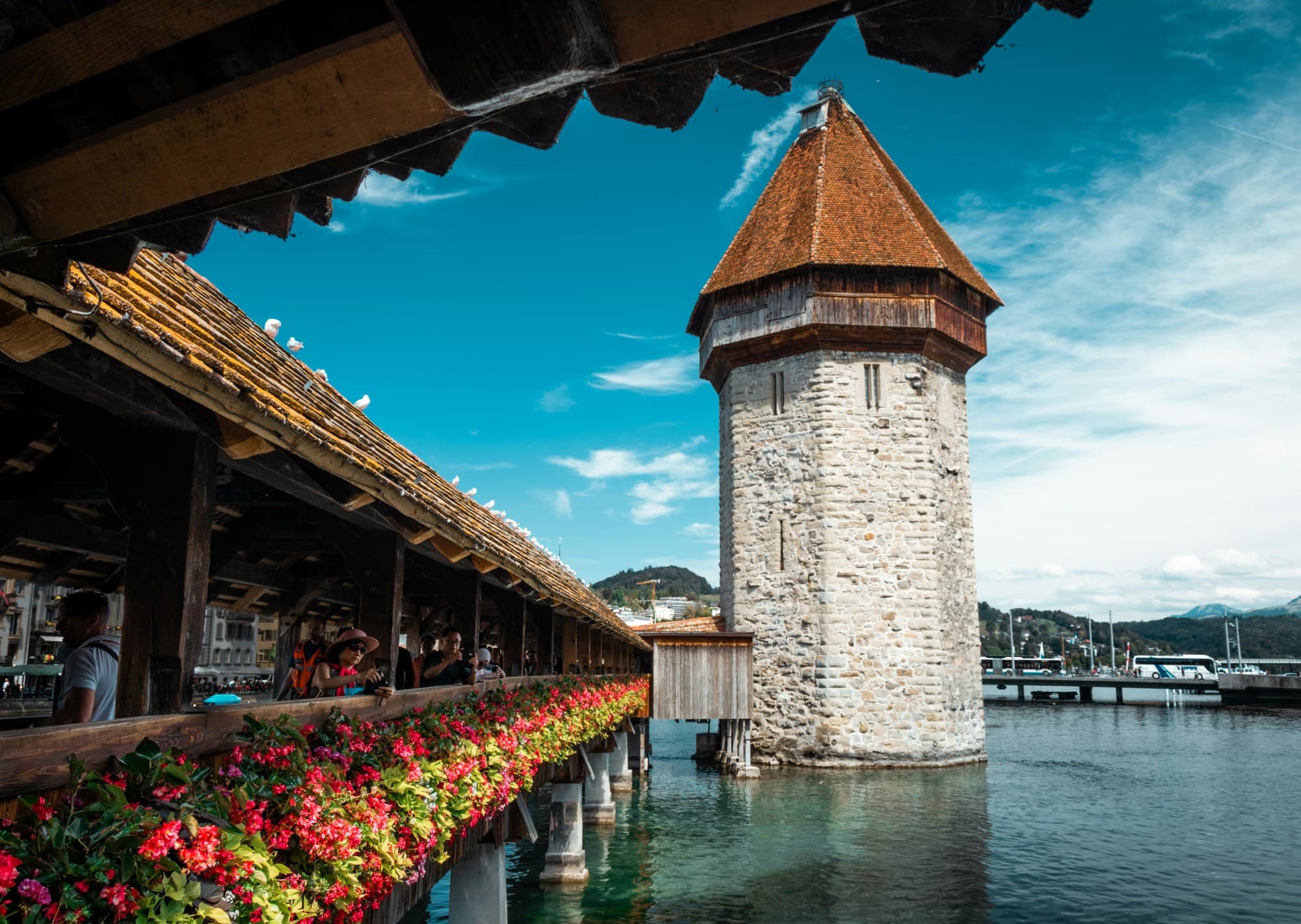 A walkway about a body of water with a tall lighthouse at the end of it