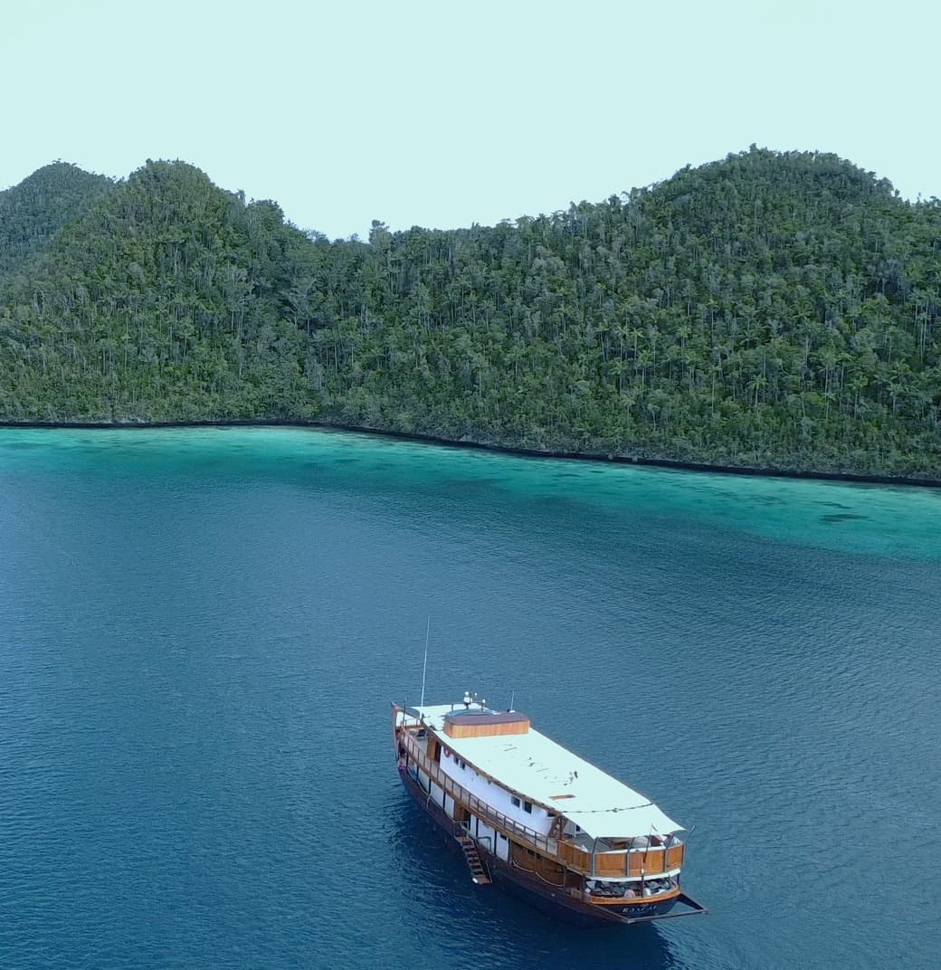 A yacht cruise in the sea with sandy enclave in the distance.