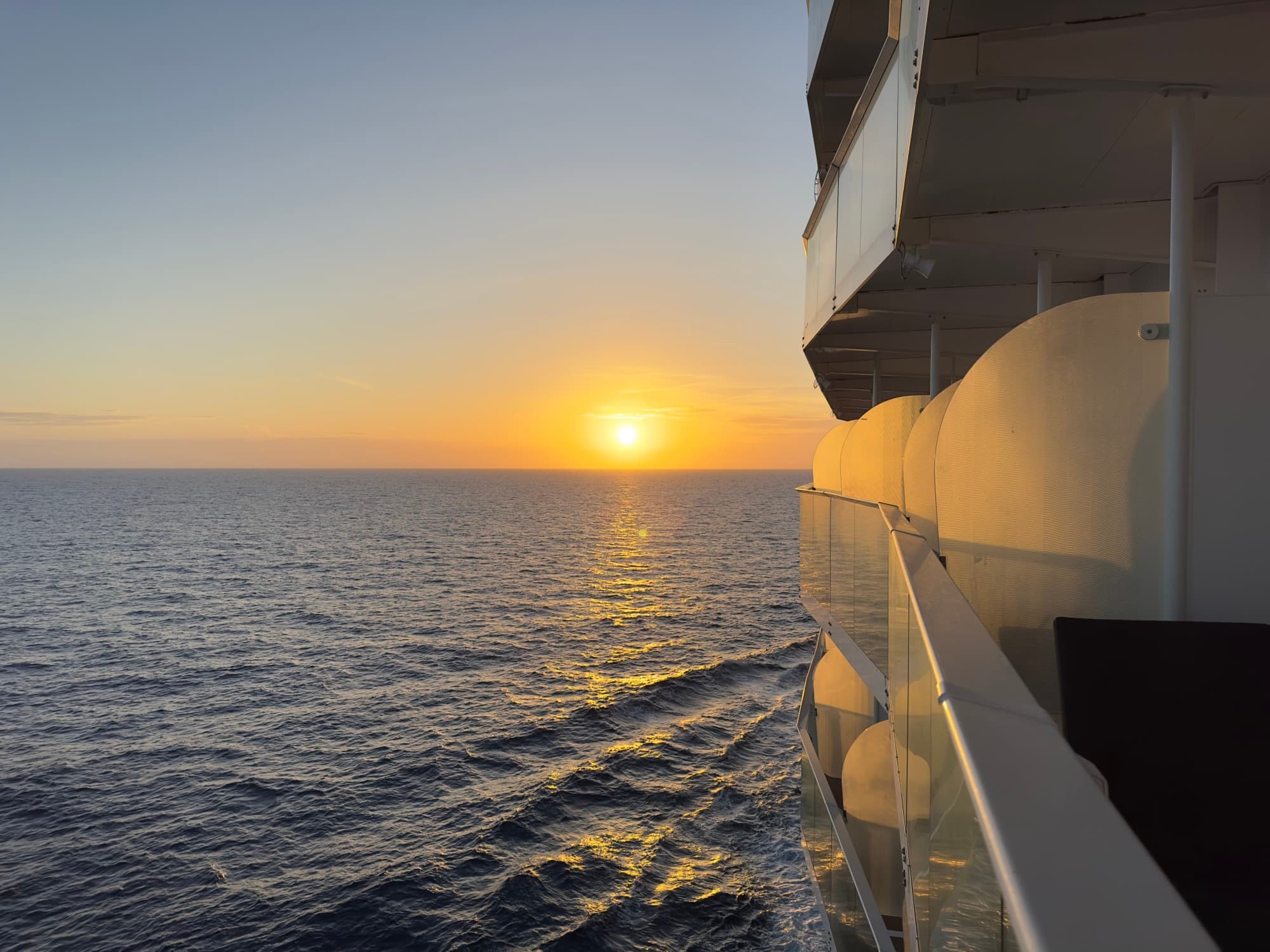 A side view of Wonder of the Seas off the Florida Coast with a beautiful sunset and the ocean waters in the distance.