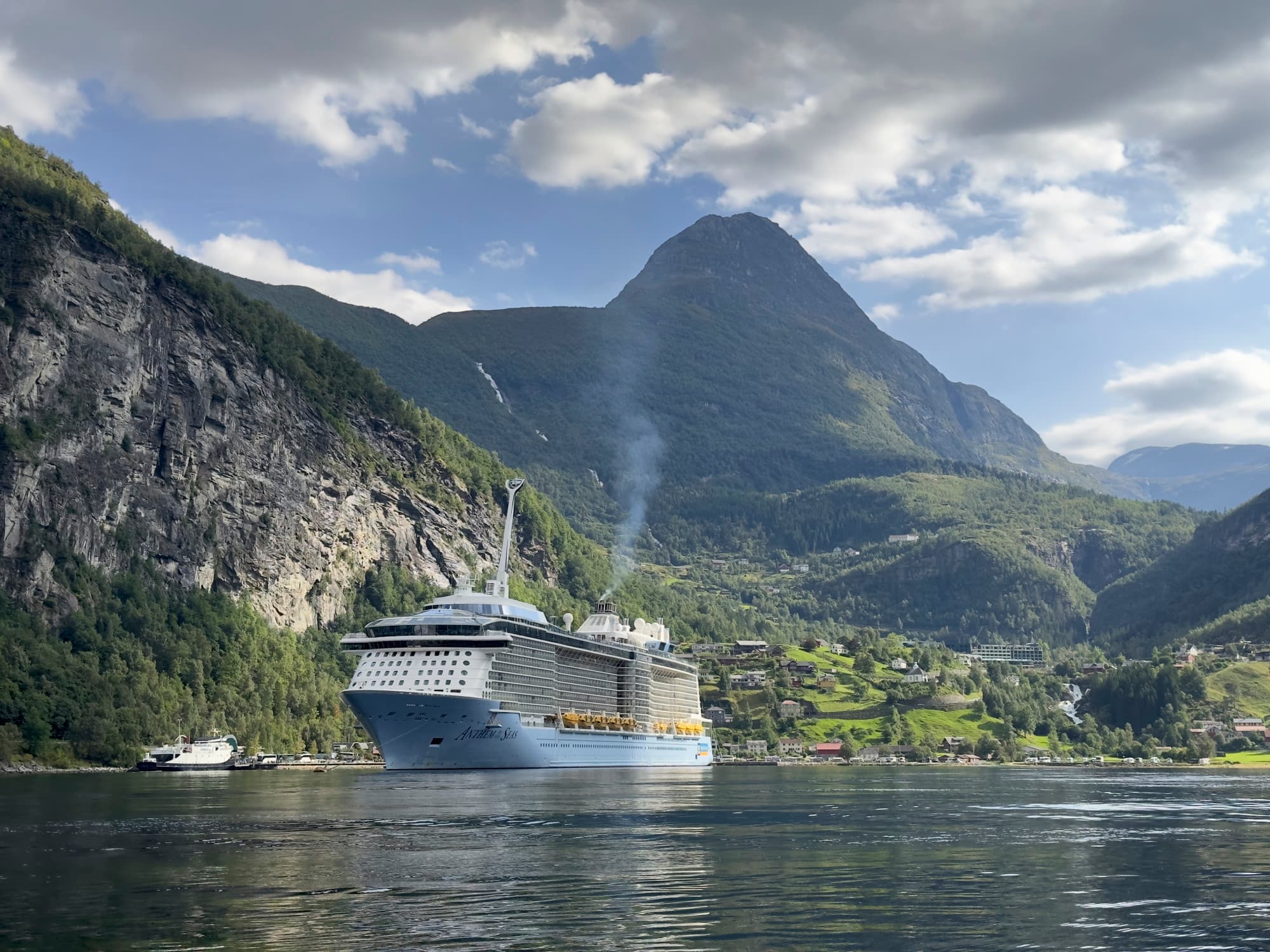 A cruise ship in the water surrounded by green mountains