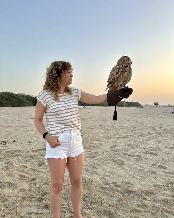 Travel advisor Alexandra standing on the sand at sunset holding an owl