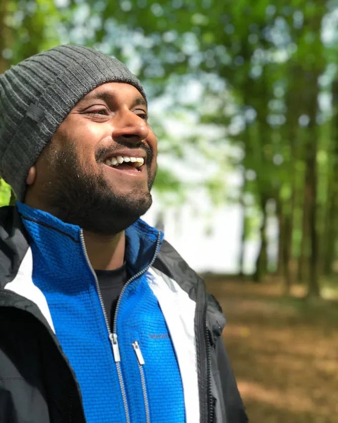 Travel advisor Bijoy smiling in an outdoor natural area with tall trees in the background