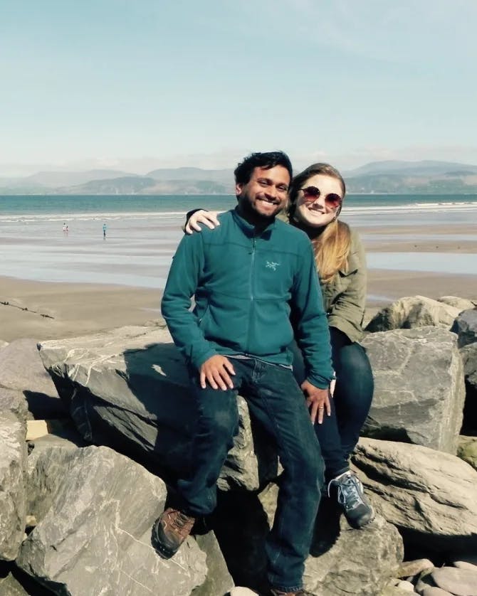 Travel advisor Bijoy Shah with female companion sitting on rocks by a beach