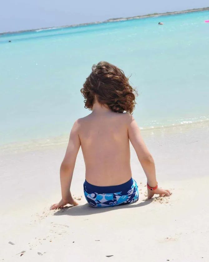 Picture of kid on beach with white sands and crystal clear water