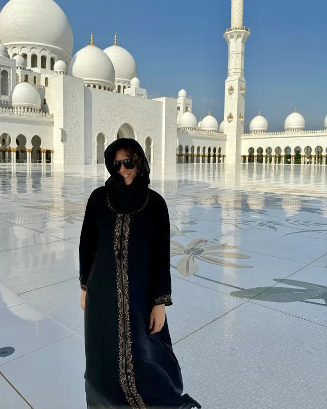 Travel advisor Alexandra standing in front a white mosque in Abu Dhabi dressed in black clothes and headscarf