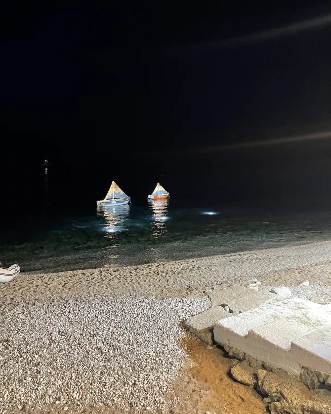 Miniature boats floating on the sea at night