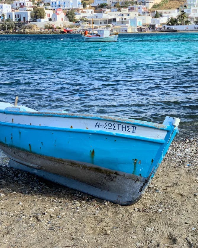 A small light blue boat on the shore 