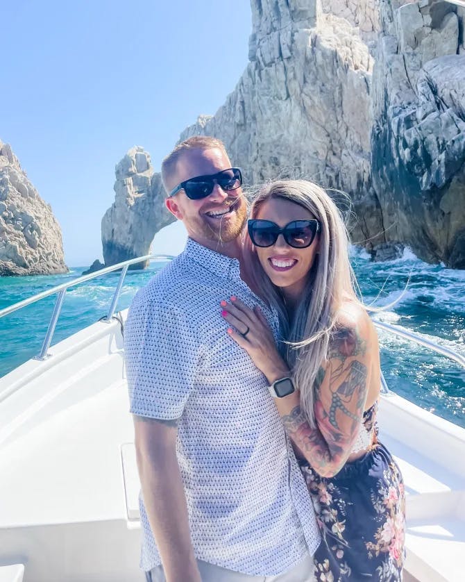 Travel advisor Lindsey with male companion smiling on a boat in front of large rock formations