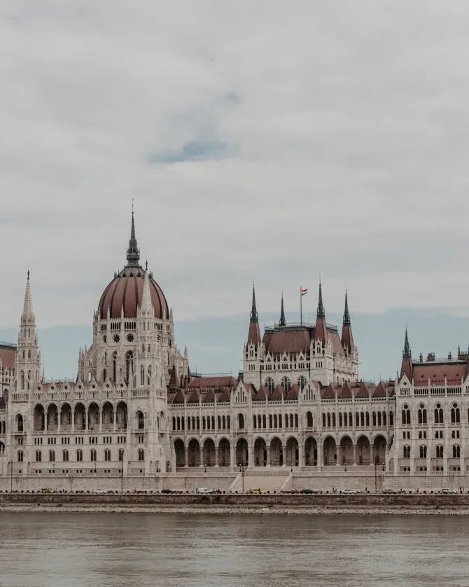 A view of Budapest on a cloudy day with a waterway and a lovely building. 