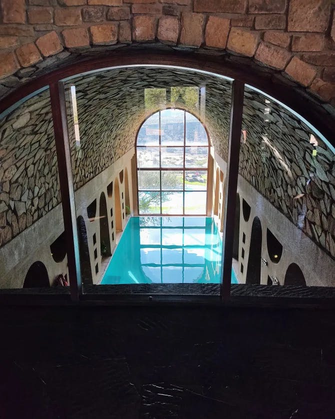 An indoor pool with a huge picturesque window and rocky ceiling.