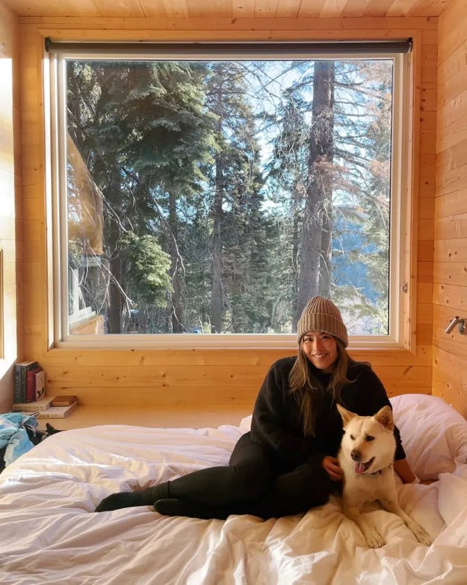 Advisor posing in a cozy hut with a dog and a nature setting outside. 