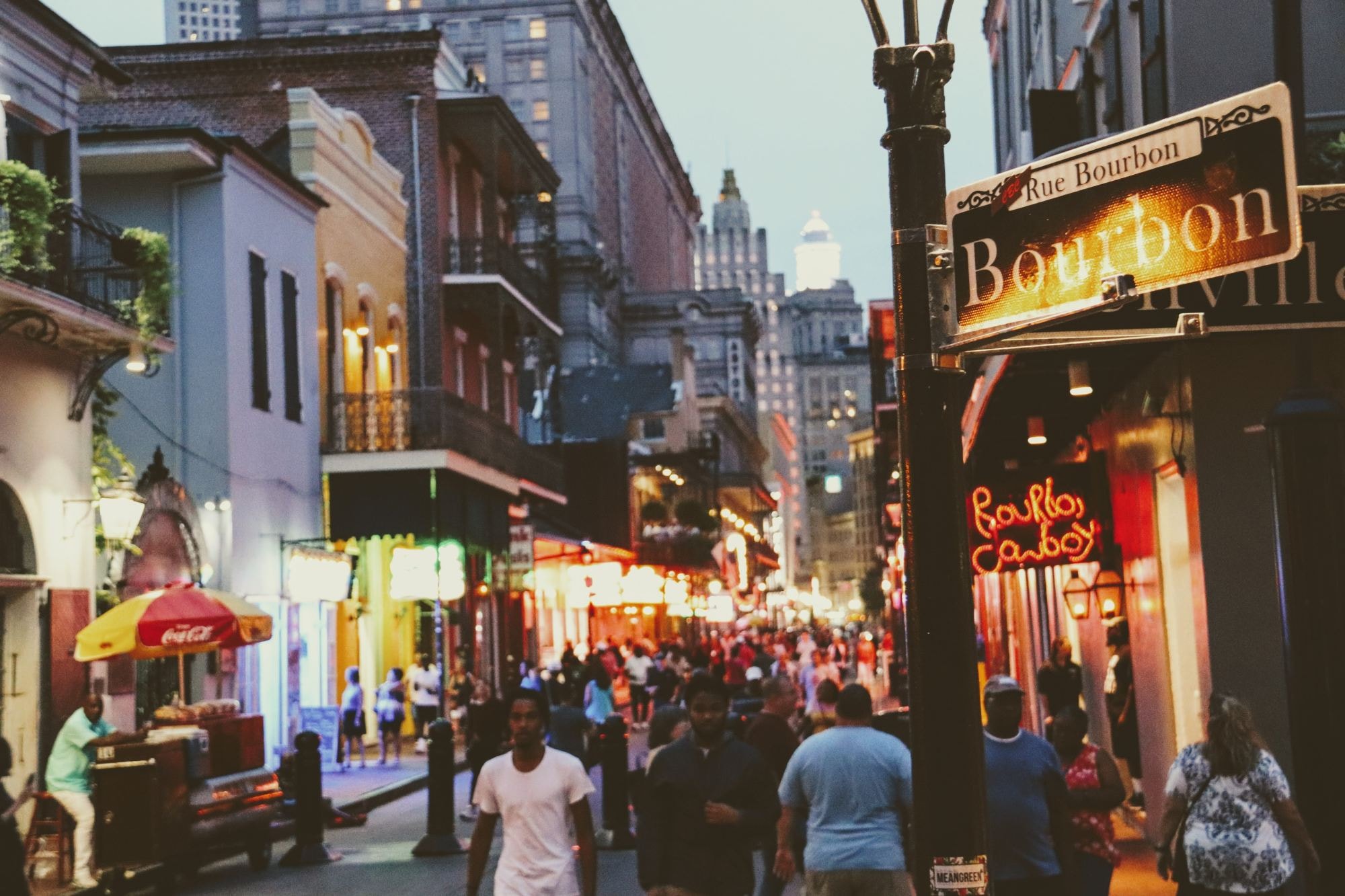 A group of people walking down a street next to tall buildings.