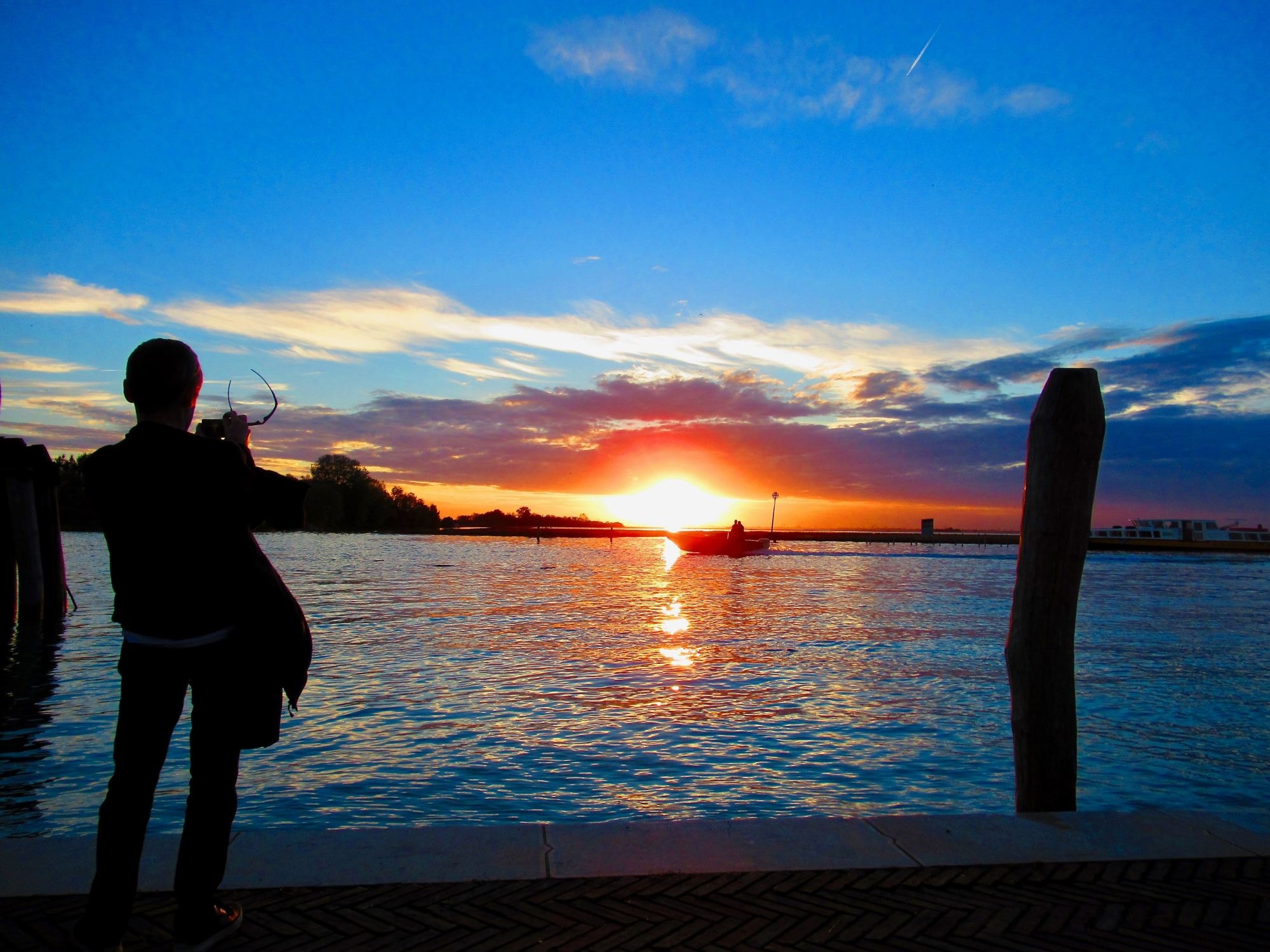 A person looking at sunset on a body of water.