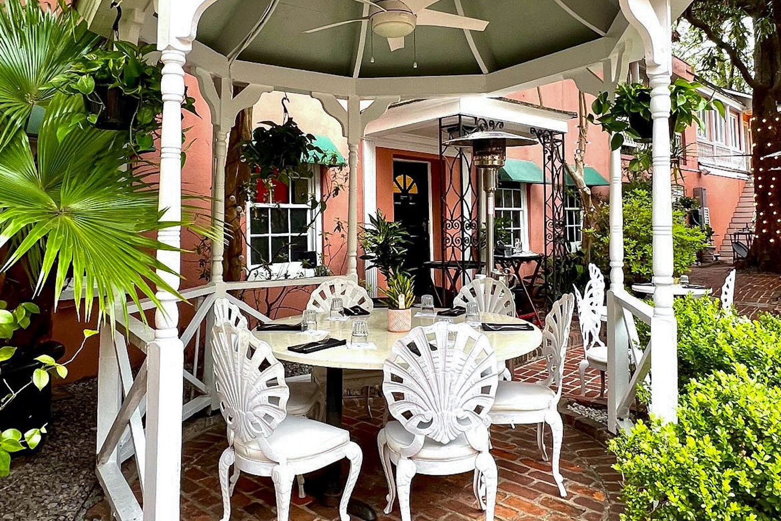 Outdoor dining with white chairs and table outside of an orange building