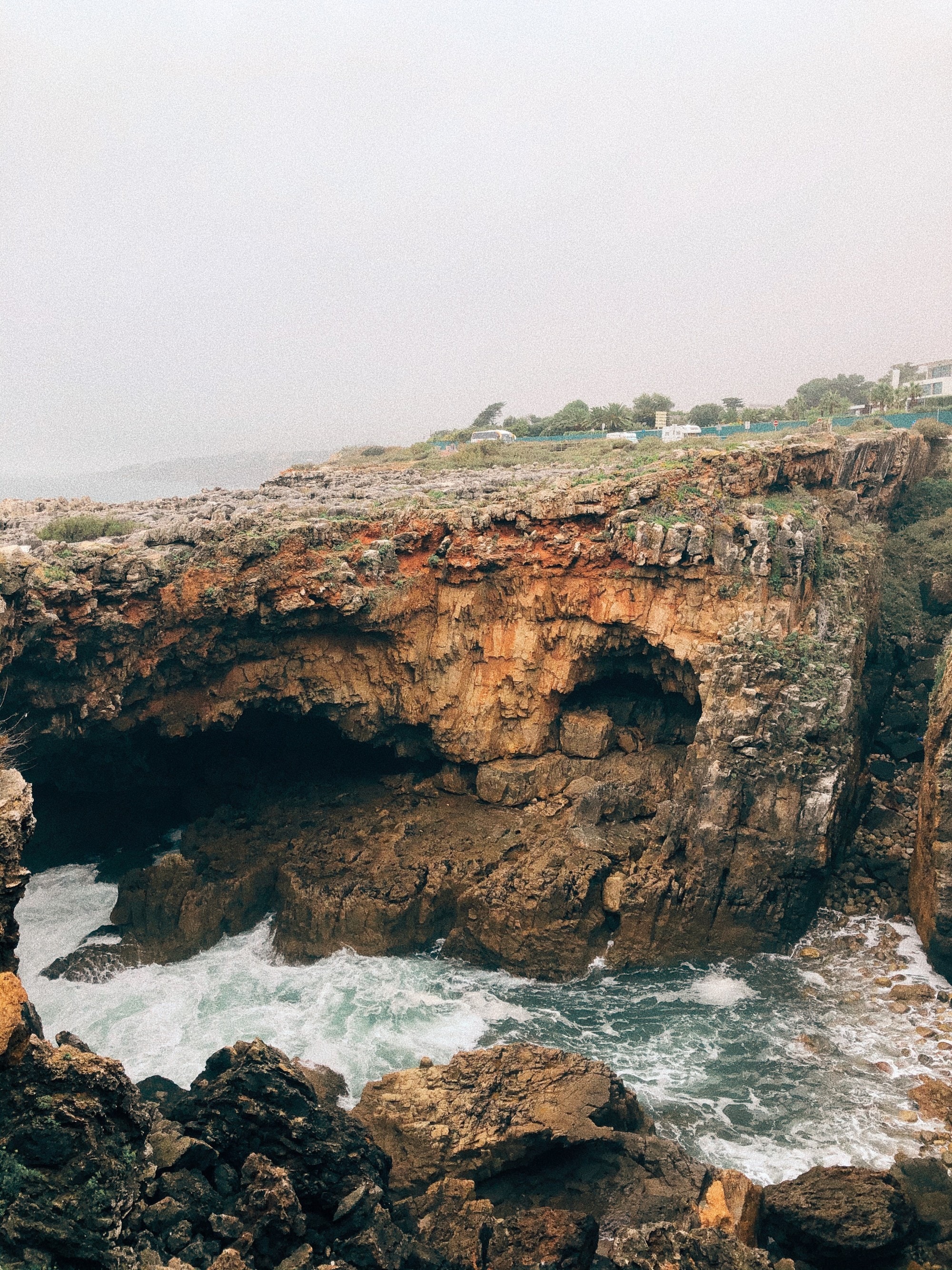 A rocky cliff overlooking a choppy sea lagoon.