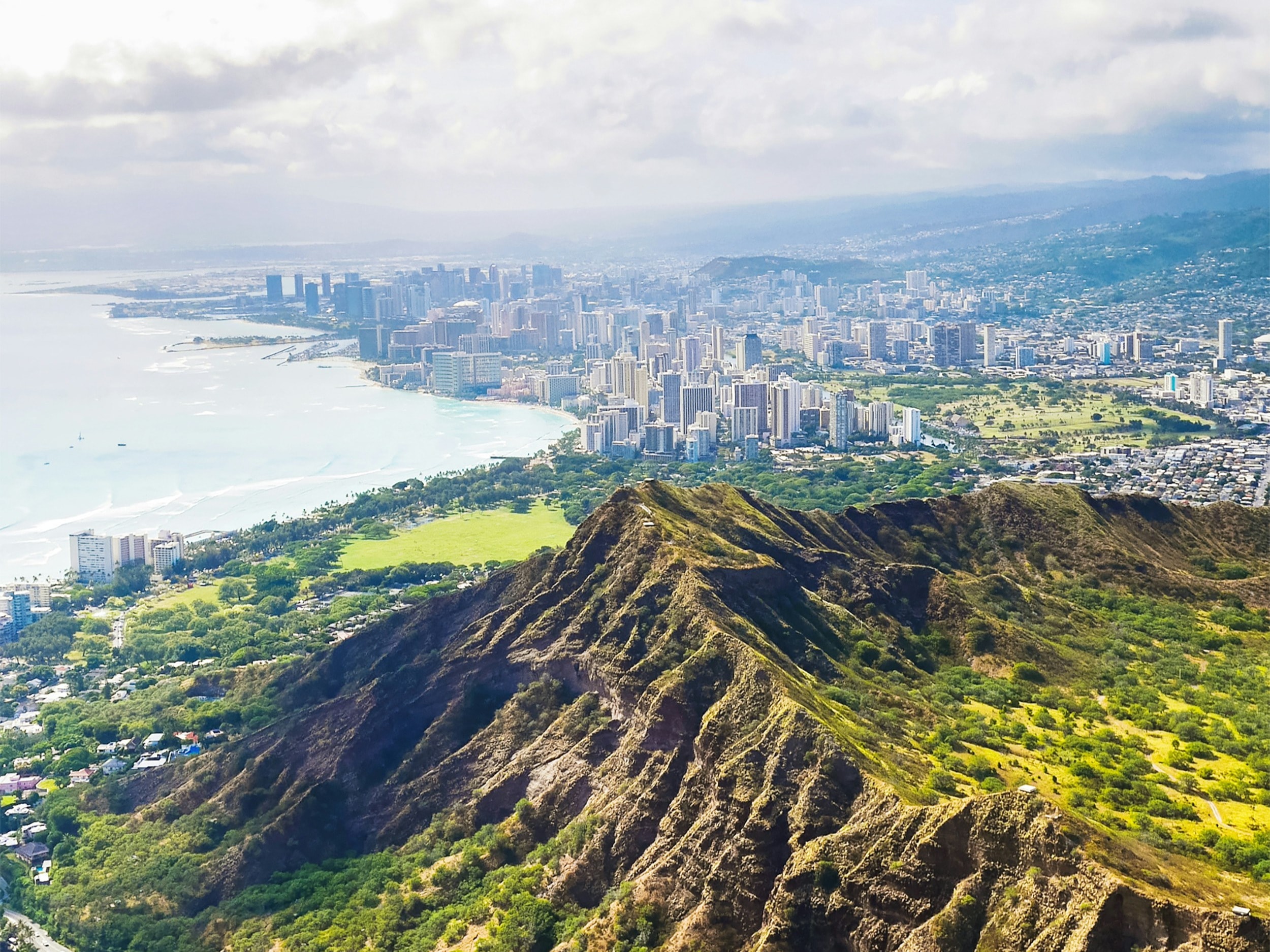 An aerial view of the island with mountains and a city in the distance