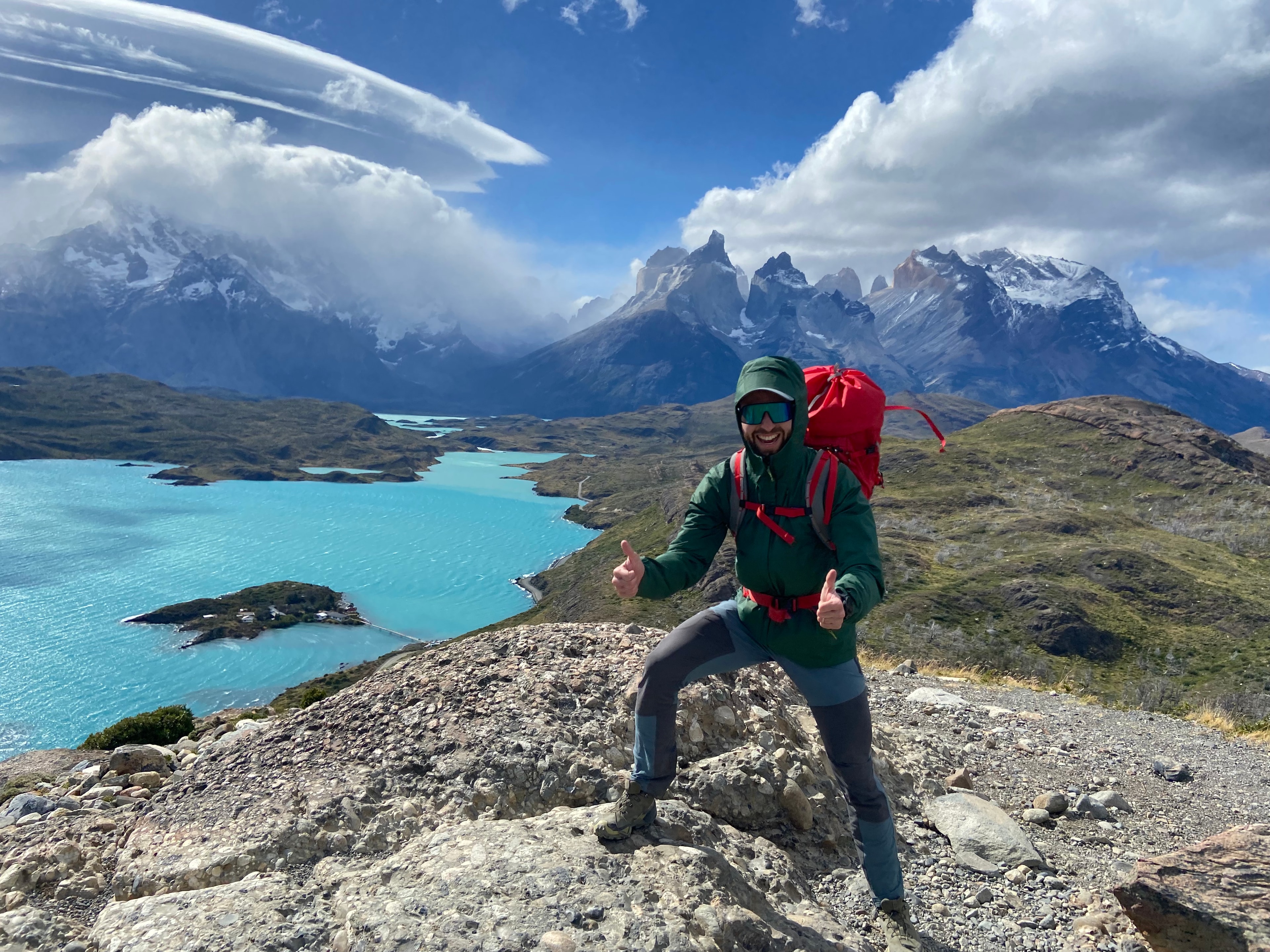 Travel advisor holding a red backpack standing beside lake