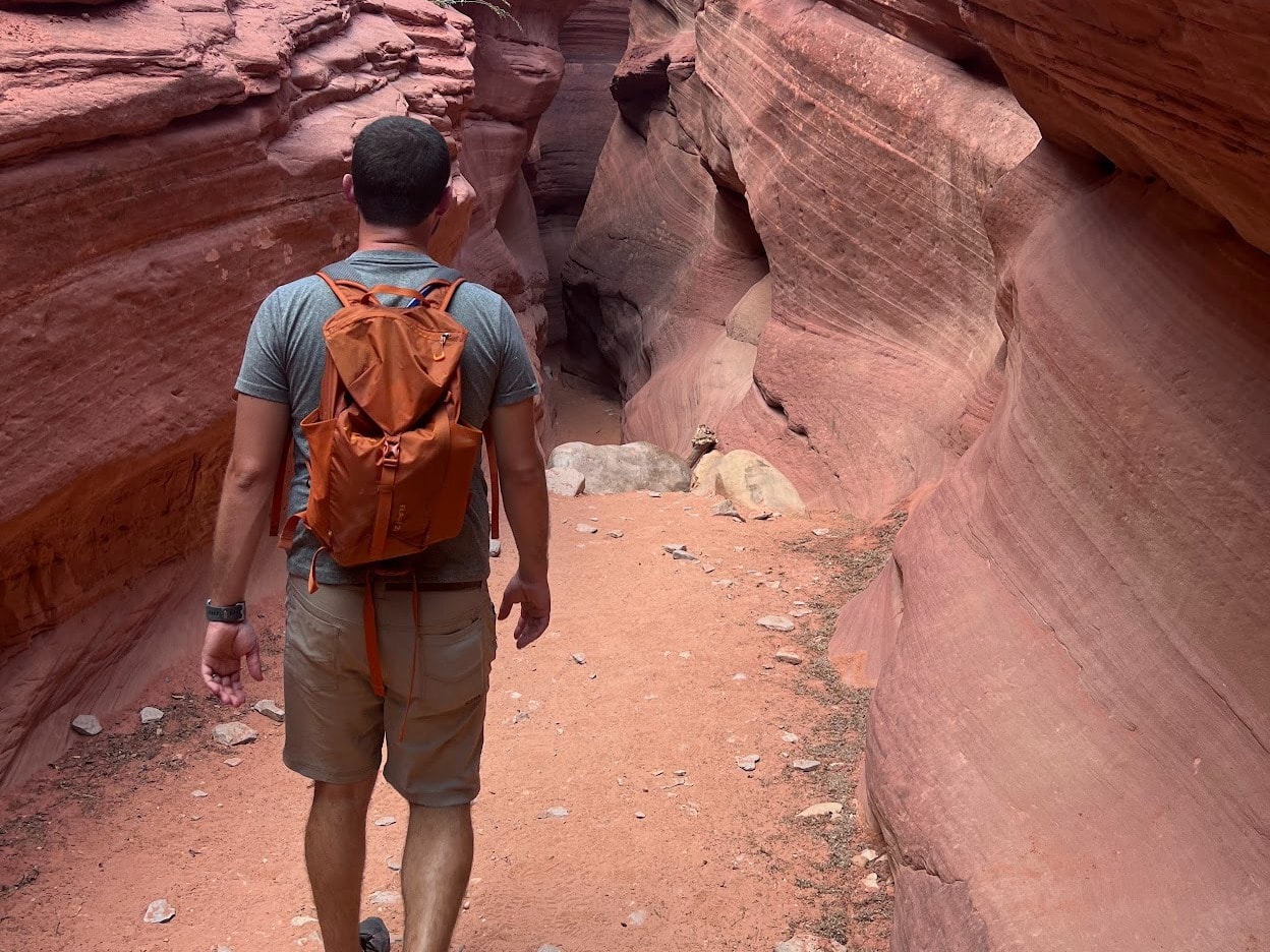 A man walking between rocky hills. 